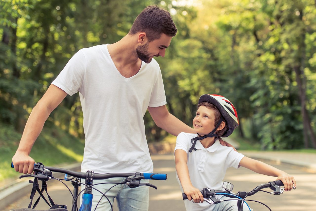 En man och ett barn leder sina cyklar på en väg