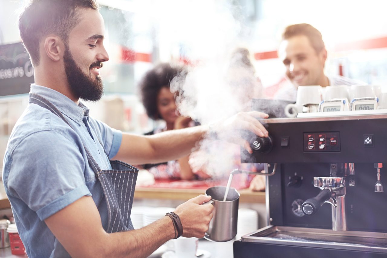 Leende barista gör kaffe på ett café
