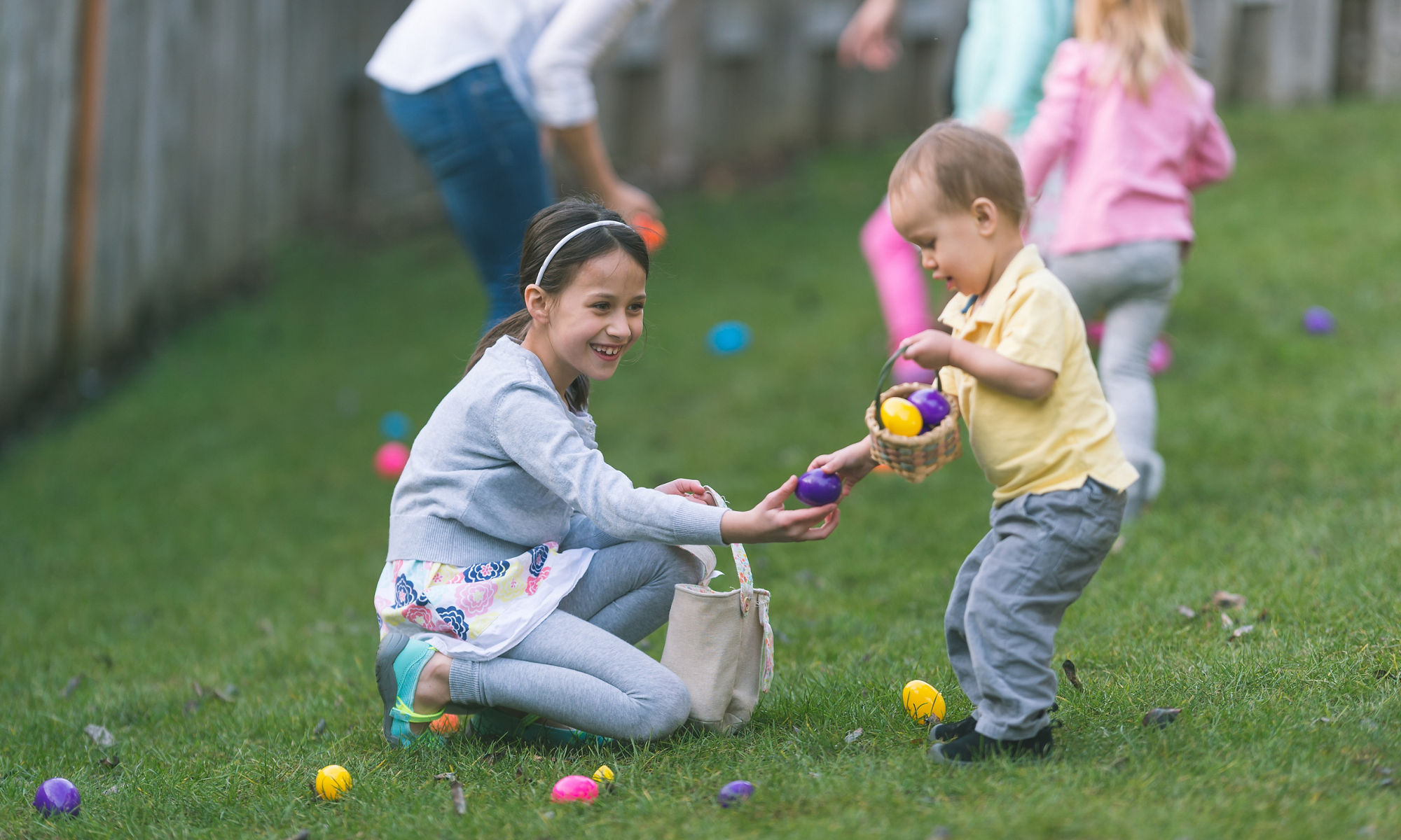 En pojke och en flicka samlar ihop påskägg i varsina korgar