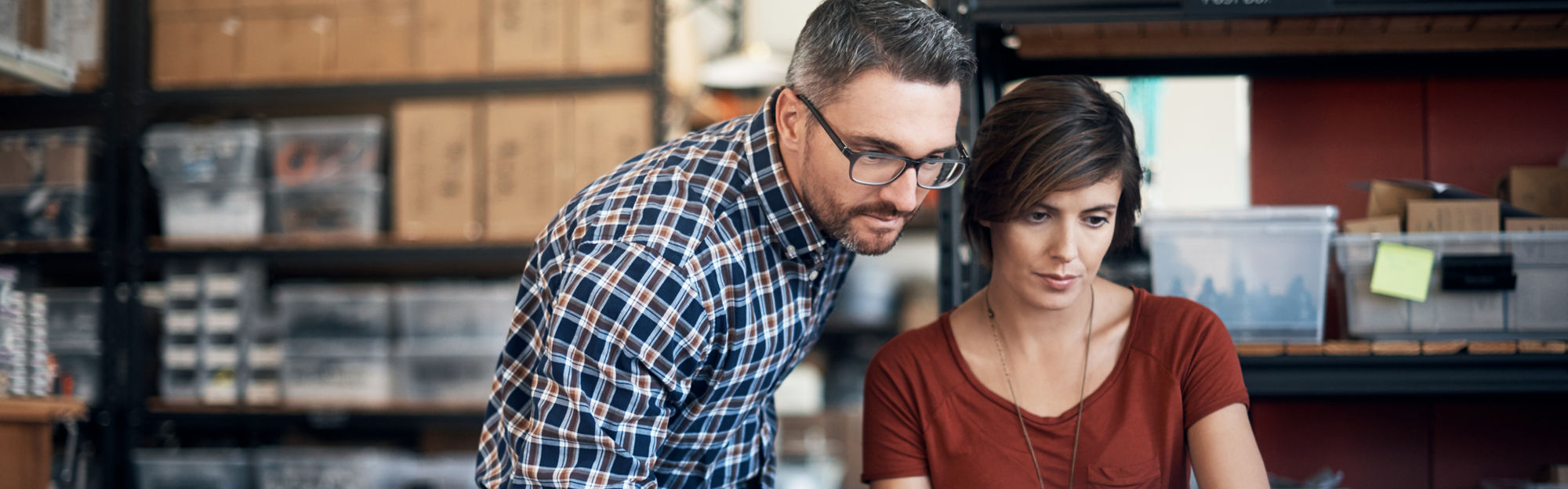 Man and woman in a warehouse using a laptop