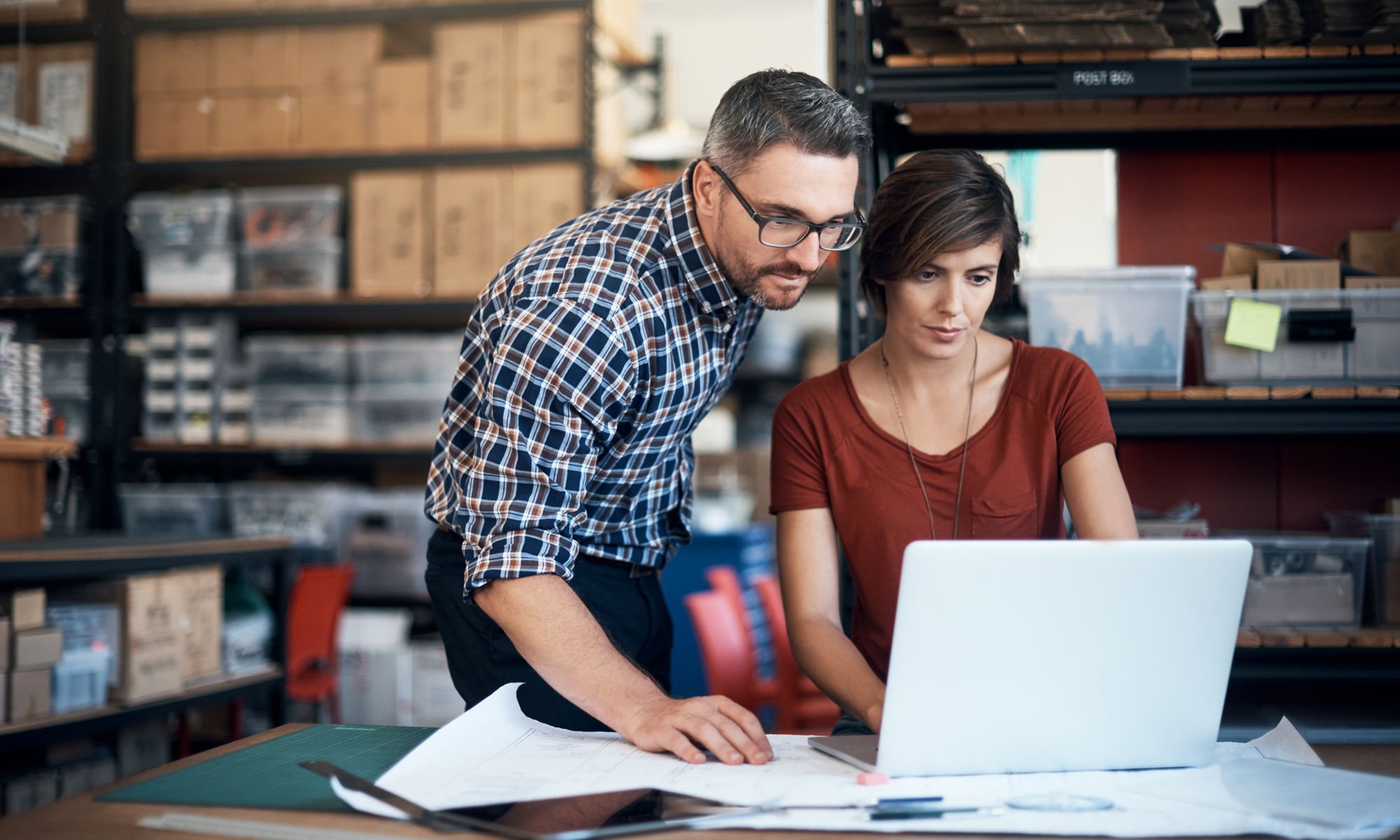 Man and woman in a warehouse using a laptop