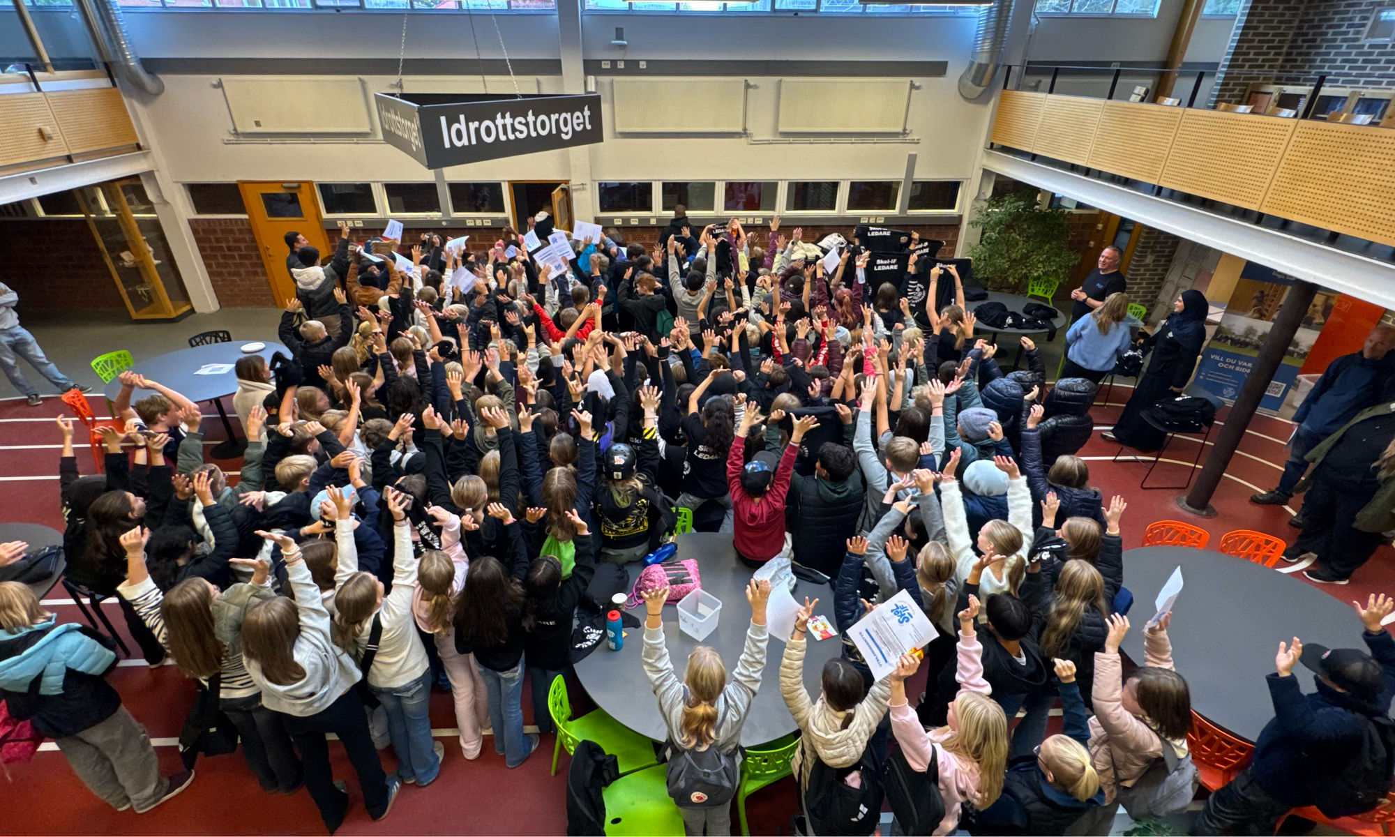 Barn står i en skola och sträcker upp händerna.