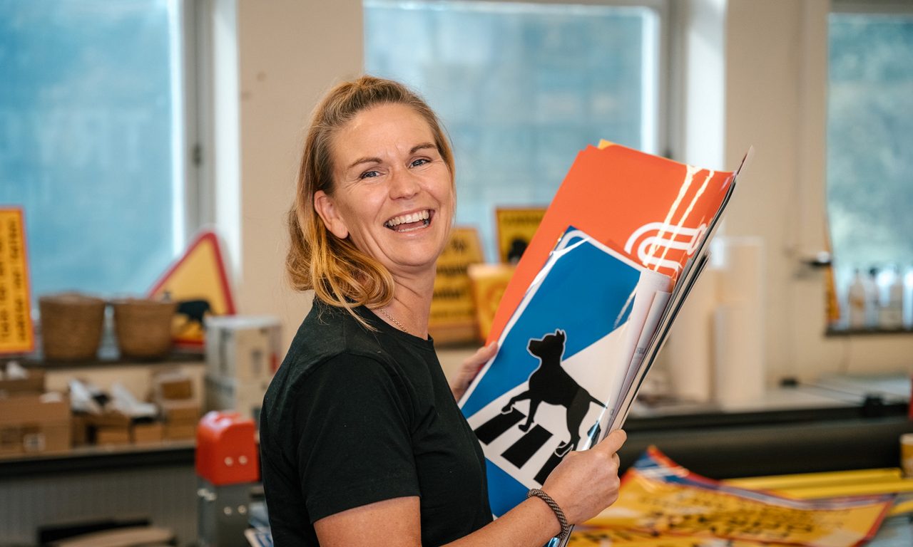 Leende kvinna håller färgglada skyltar i tryckeri.