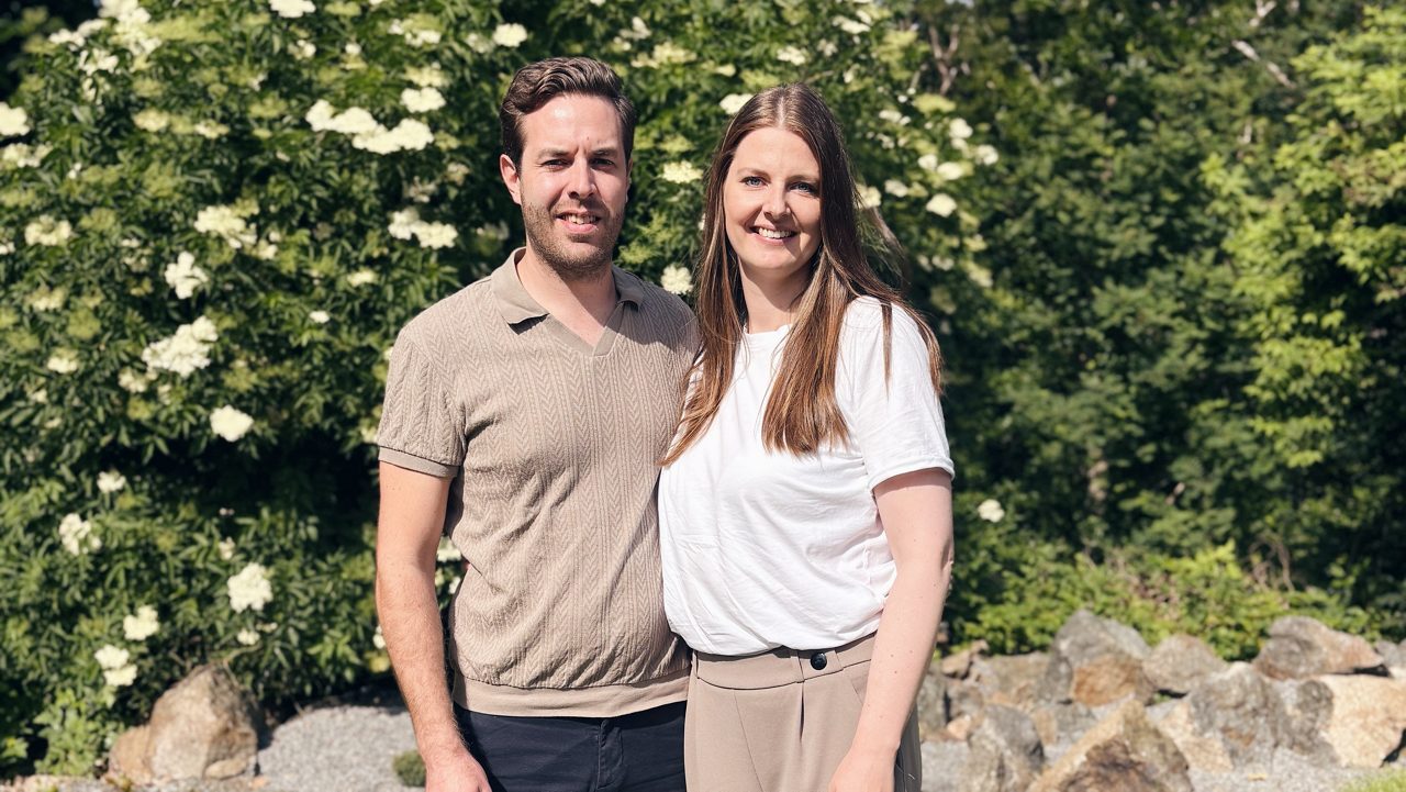 Två glada personer som står i en trädgård