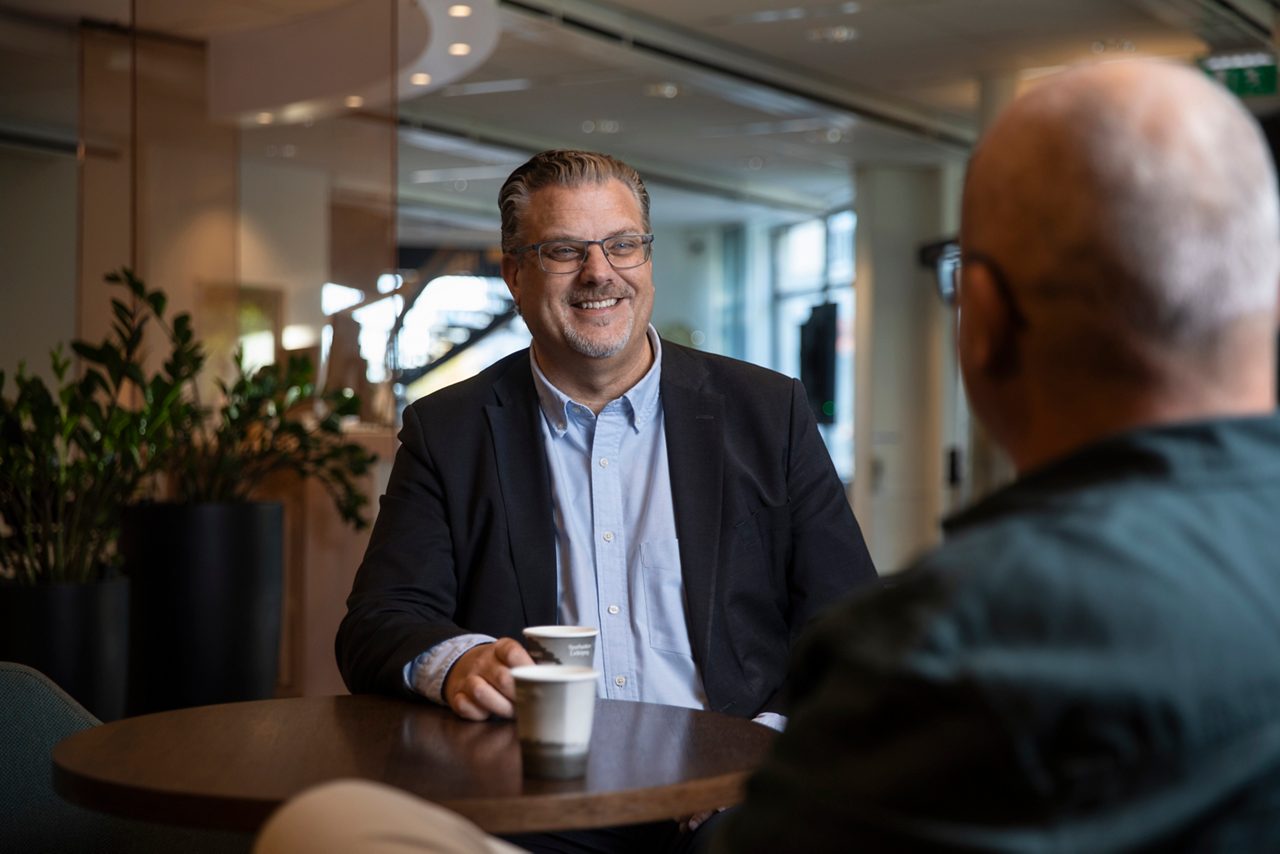 En av bankens privatrådgivare sitter vid ett bord med en kopp kaffe