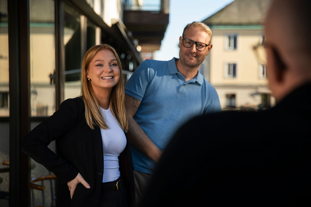 Tre kollegor står och pratar med varandra på balkongen