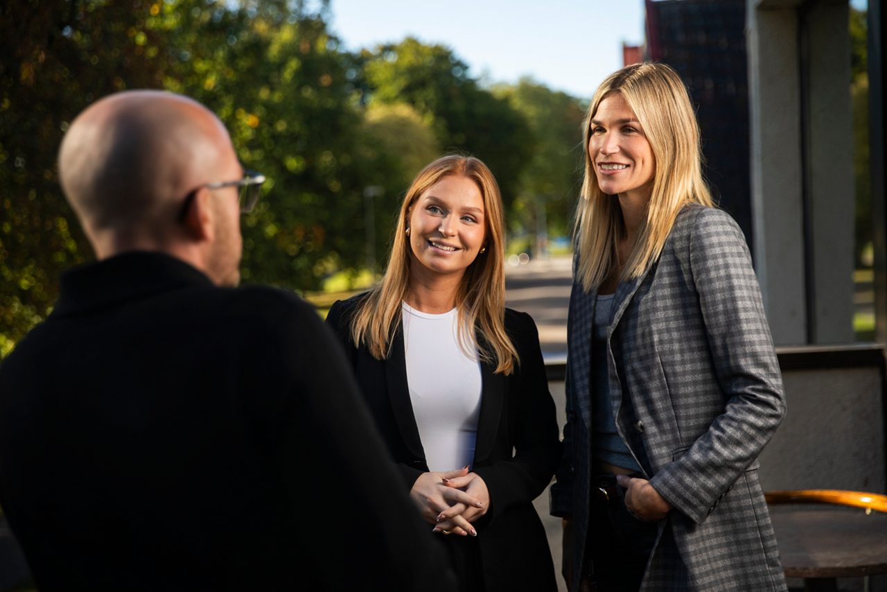 Tre kollegor står och pratar med varandra på balkongen