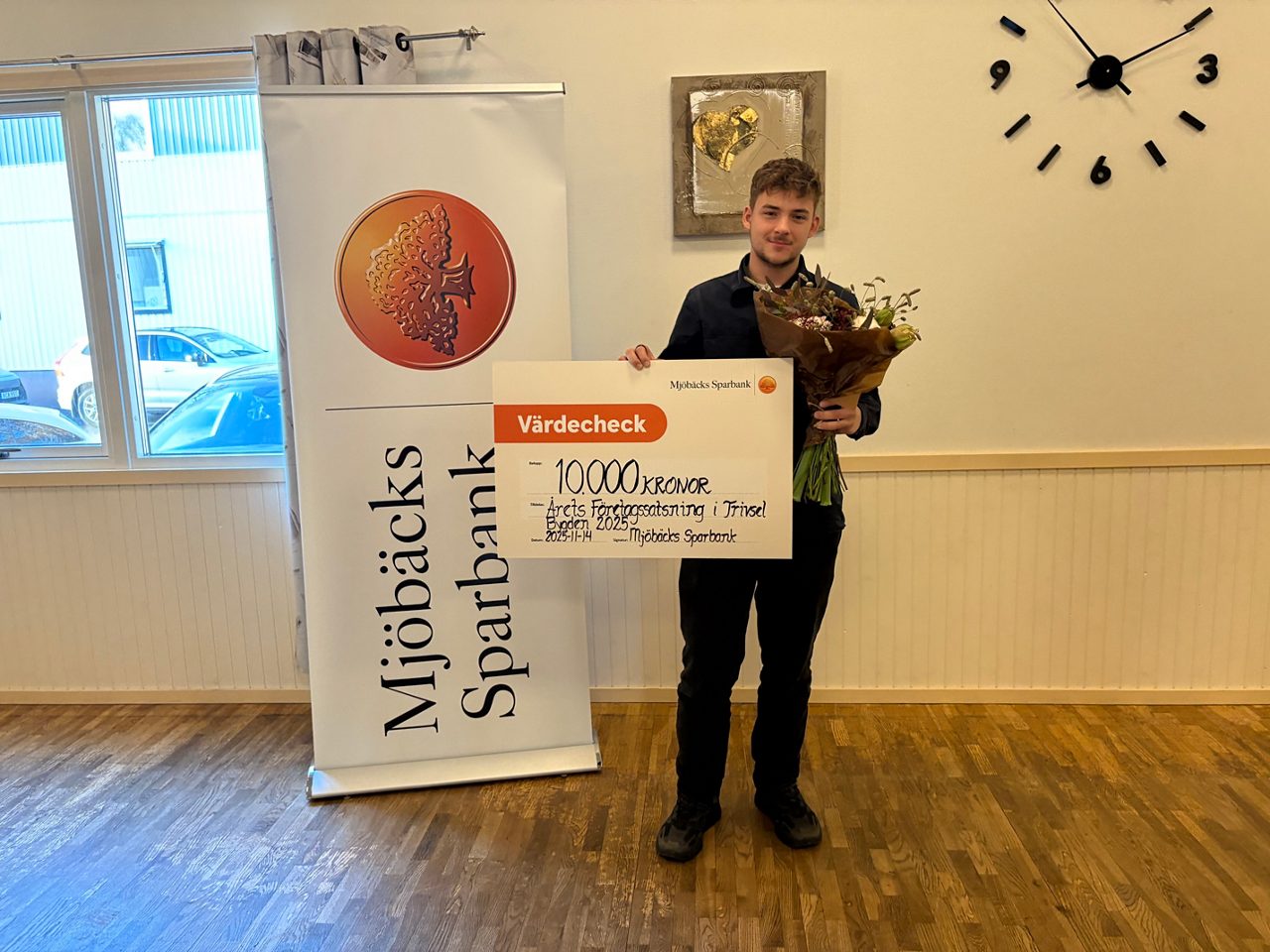 Finn från Finns mek och service står med vinstchecken på 10.000kr och tittar in i kameran och ler