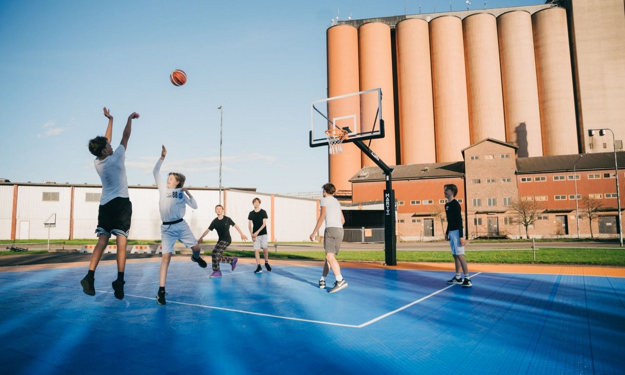 Ungdomar som spelar basket. Lantmännens silos i Falkenberg syns i bakgrunden. 