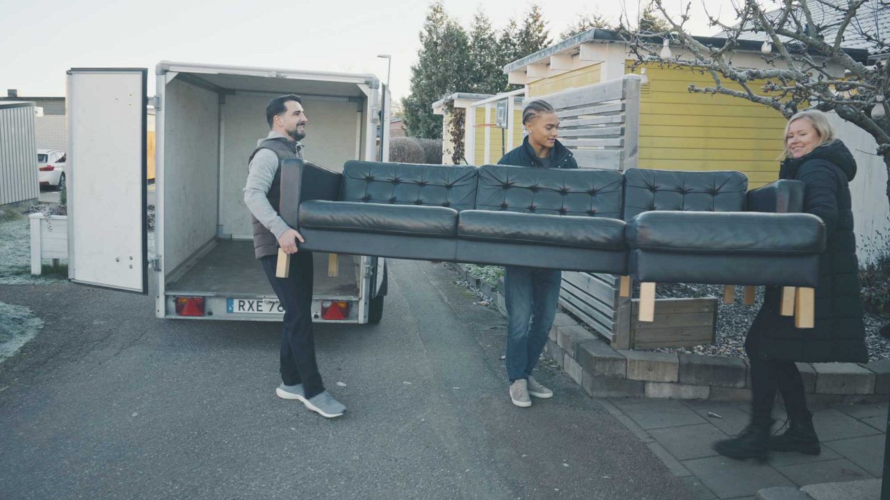 tre personer bär en soffa