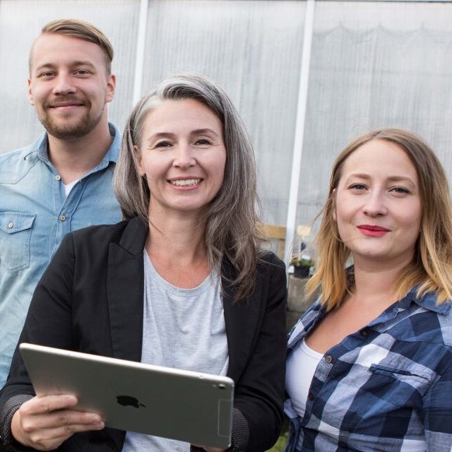 En man och två kvinnor står utomhus och ler mot kameran