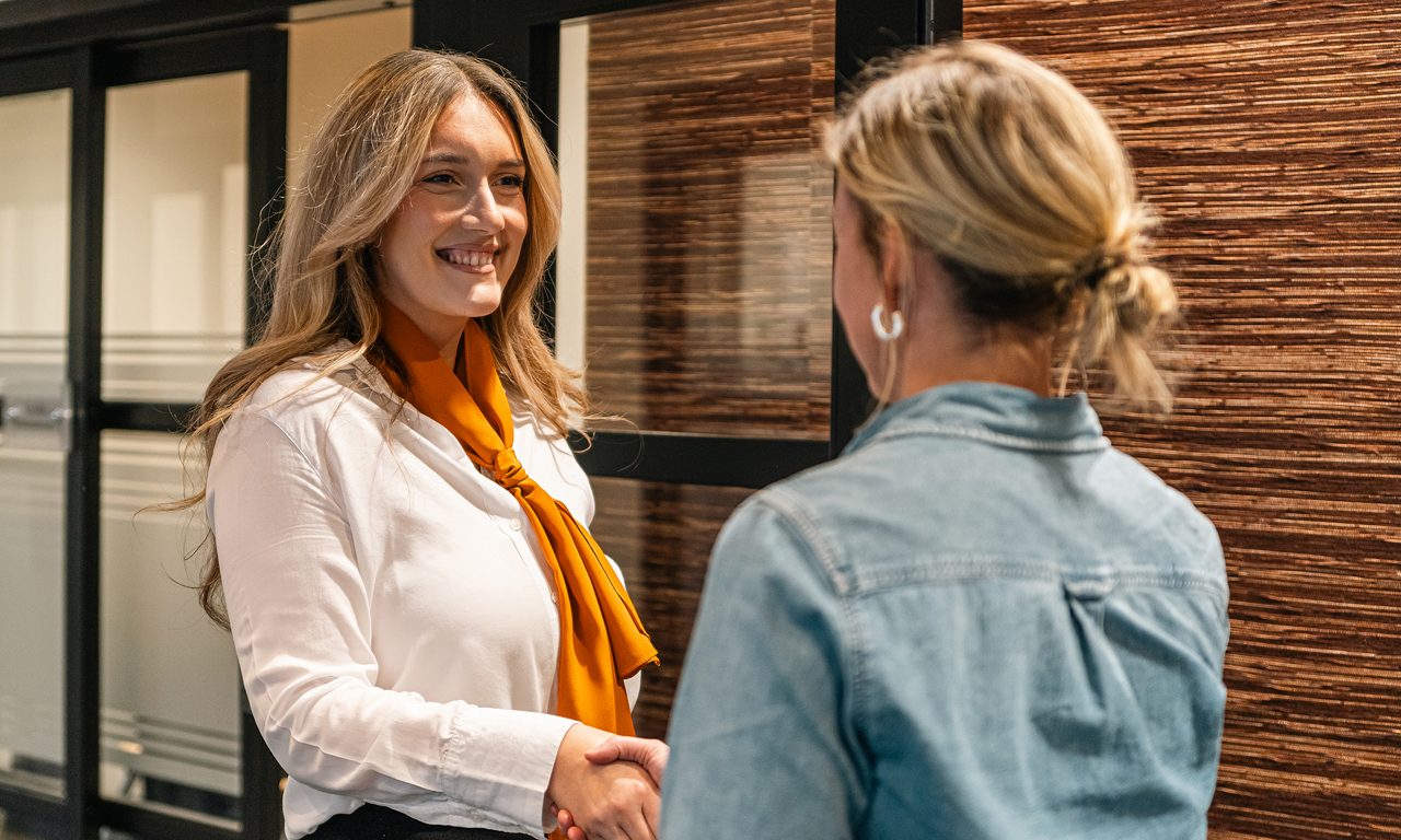 En kvinna hälsar på en annan kvinna i hand