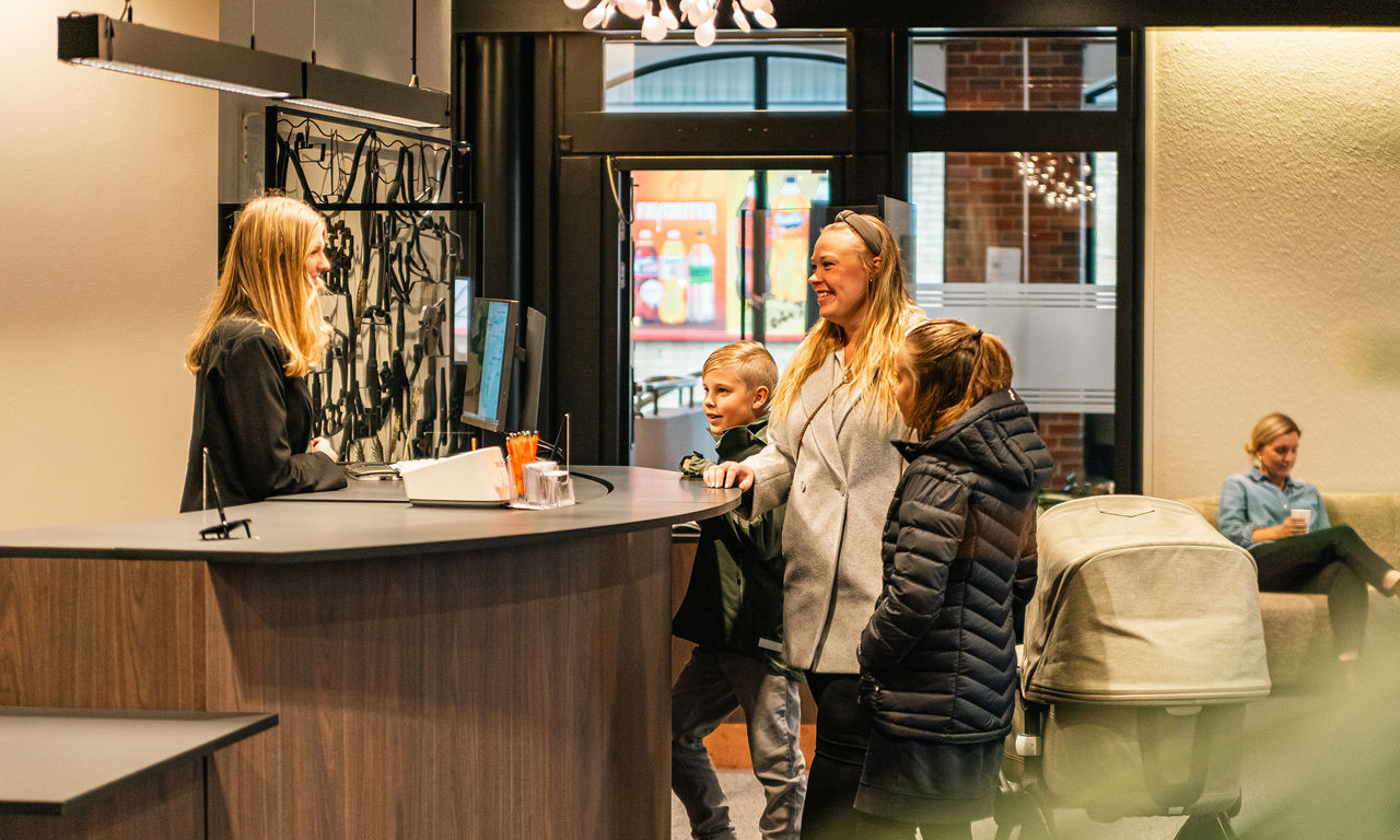 Kvinna med barn står vid kassan hos en bank