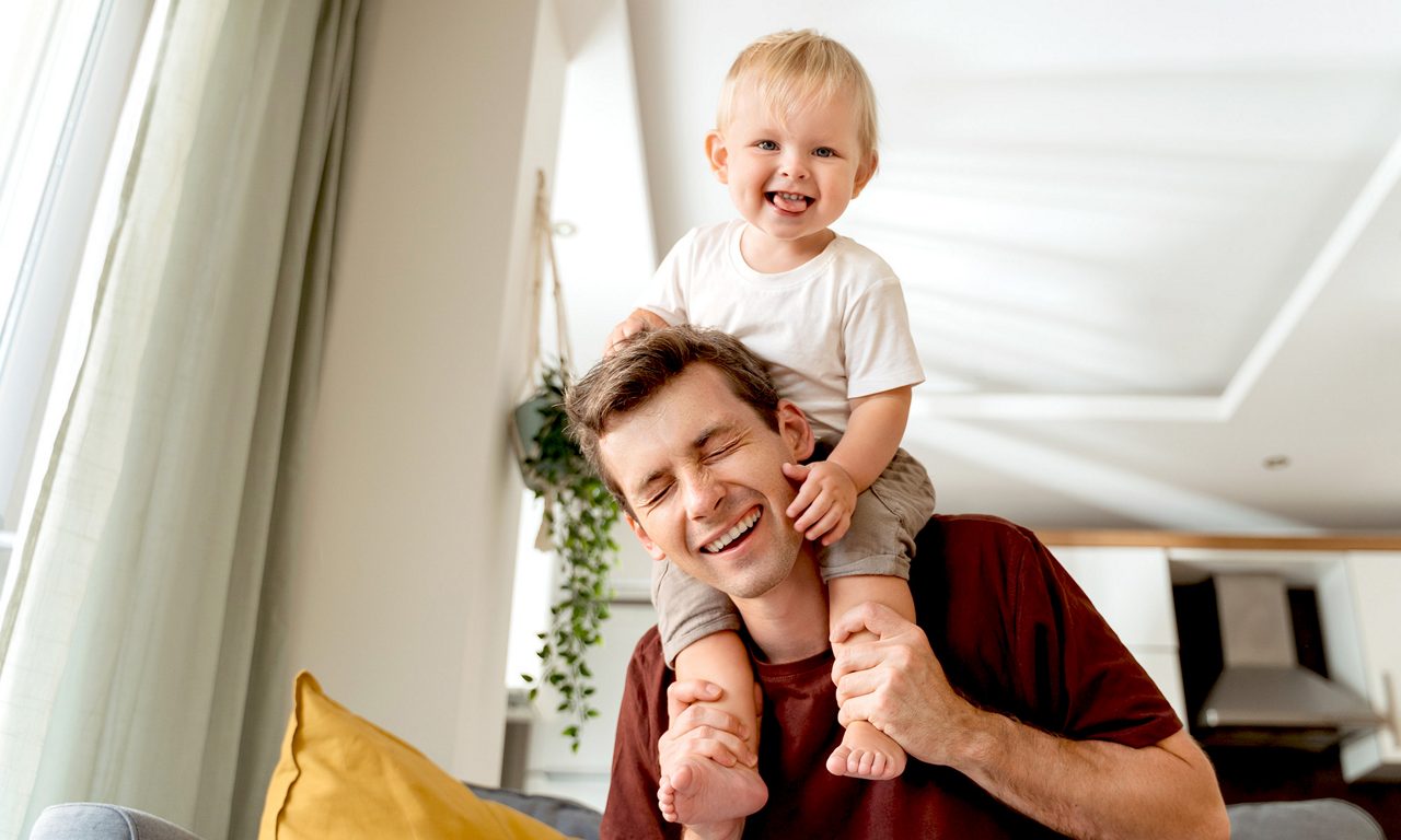 En kille som har ett litet barn på sida axlar.