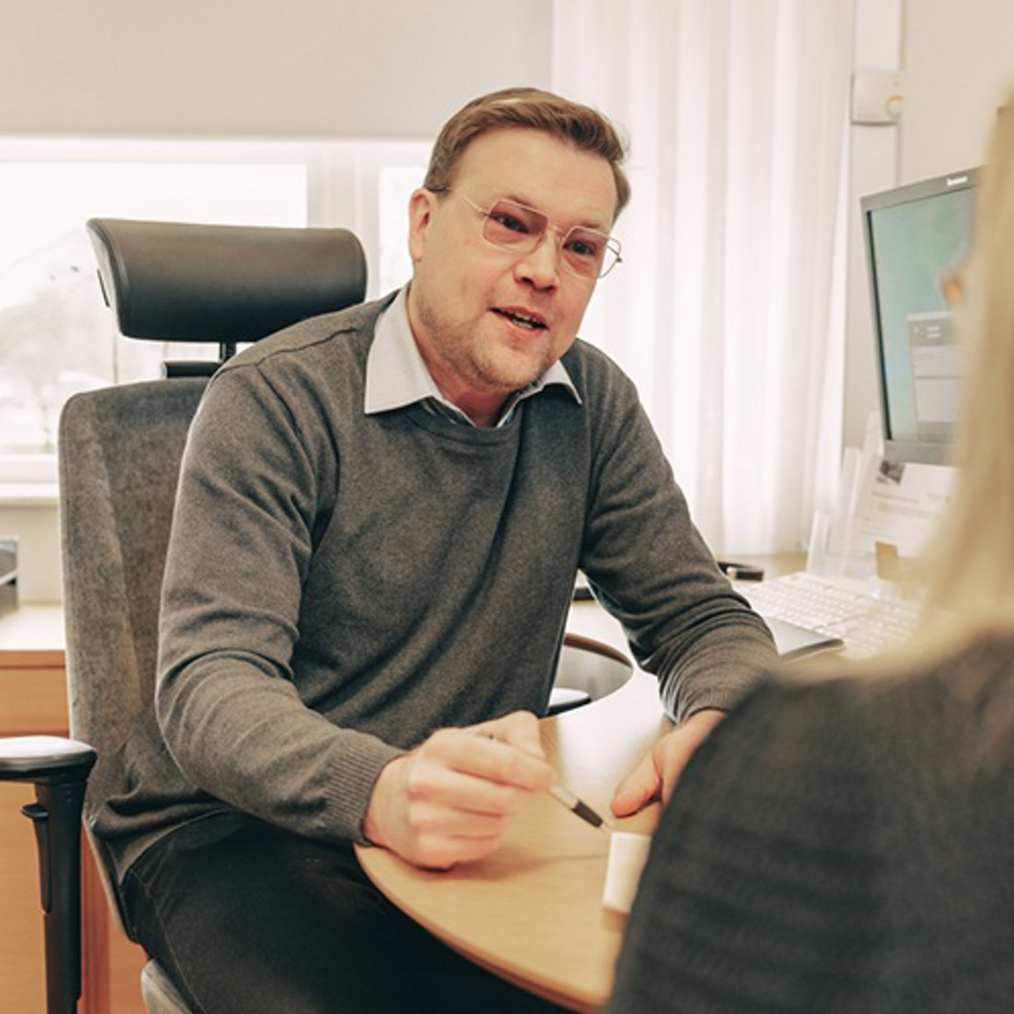 Kristoffer pratar med en kund vid ett skrivbord