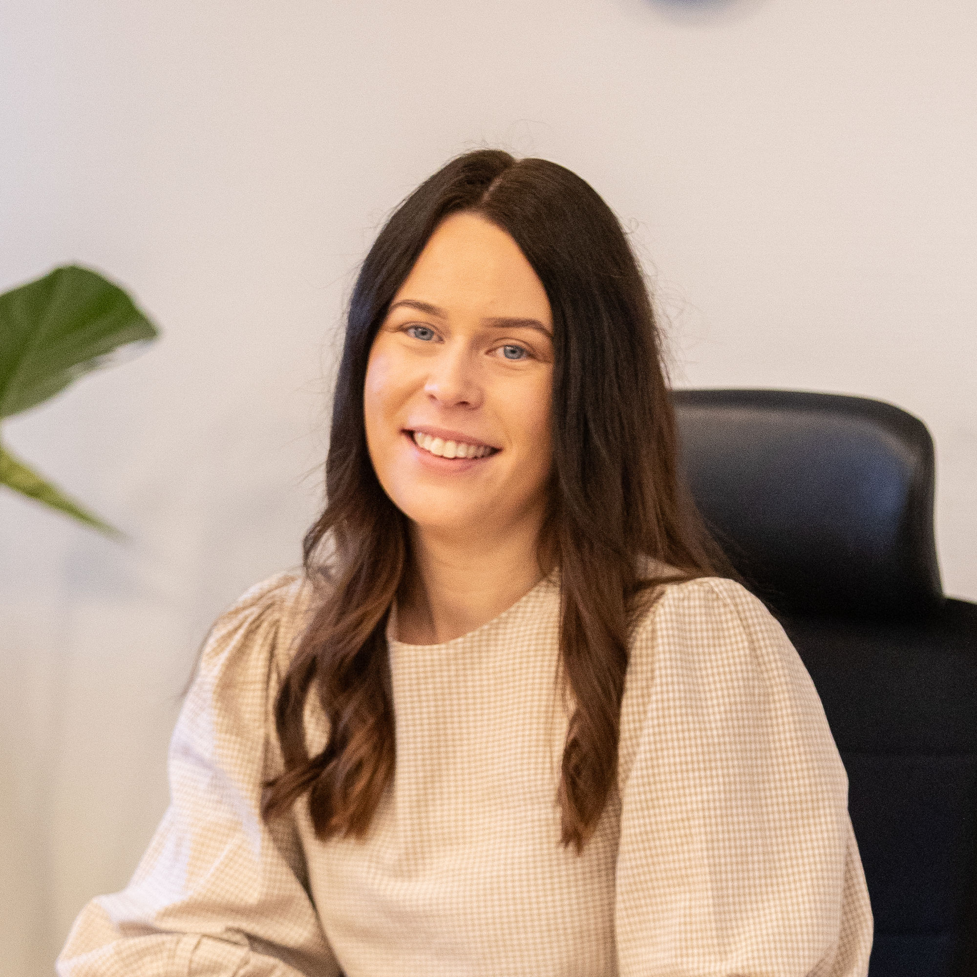 Linn som är rådgivare på banken sitter bakom ett skrivbord och ler stort.