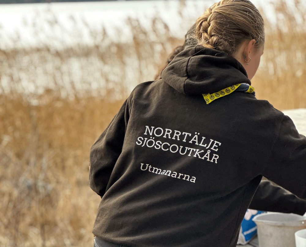Ryggen på en flicka med en jacka med texten "Norrtälje Sjöscoutkår"