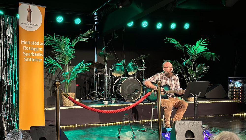 Man med gitarr spelar på en scen