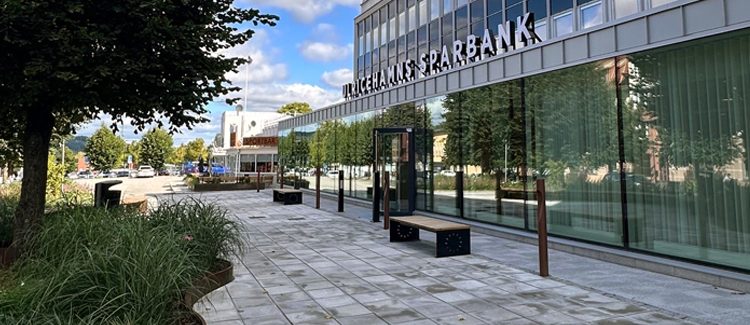 Framsida av ett bankkontor med glaspartier och växtlighet framför 