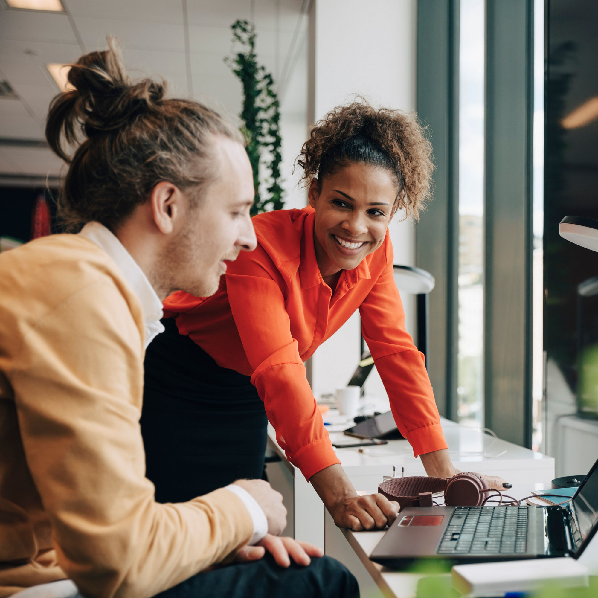 En kvinna och en man som arbetar tillsammans på kontoret vid en bärbar dator.