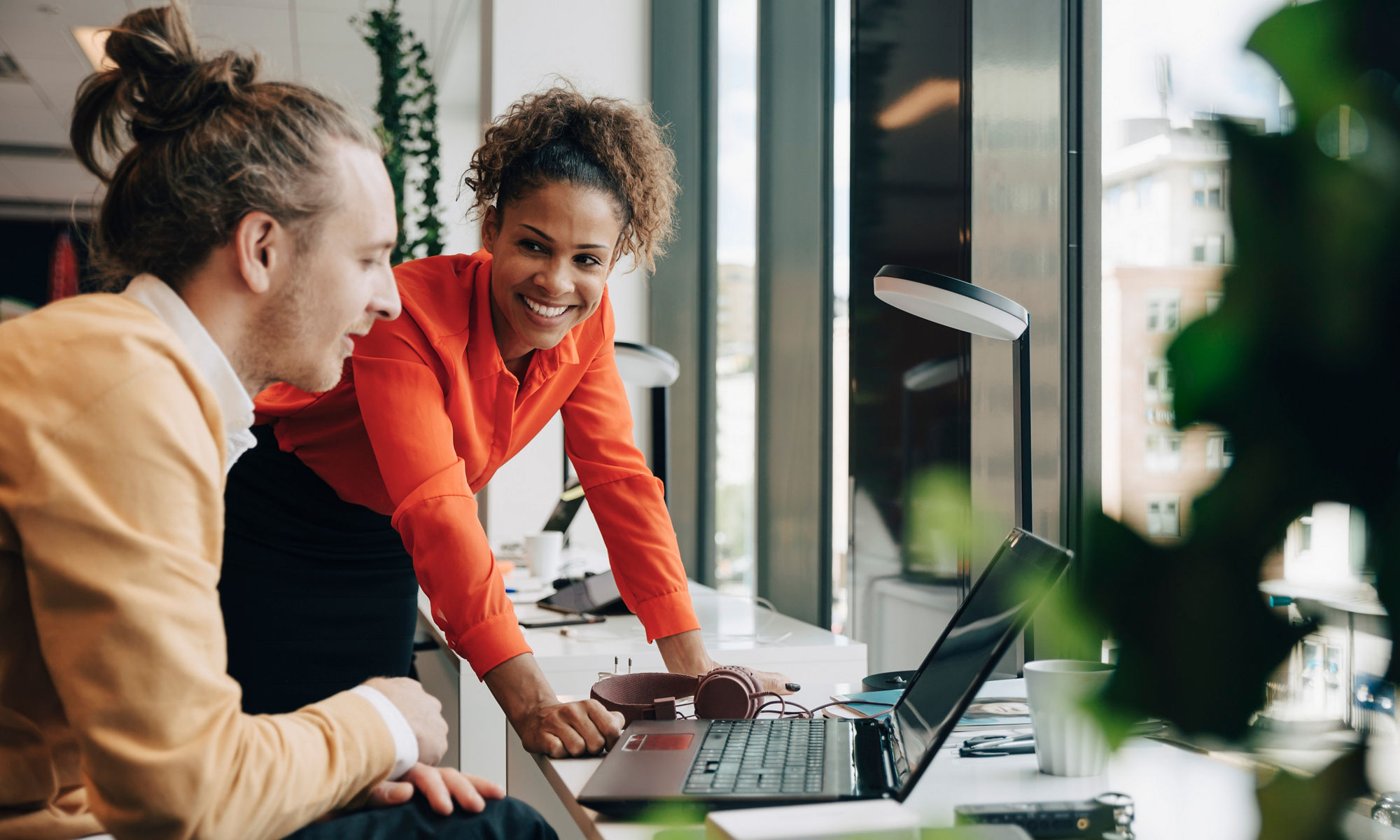 A woman and a man working together at the office by a laptop.