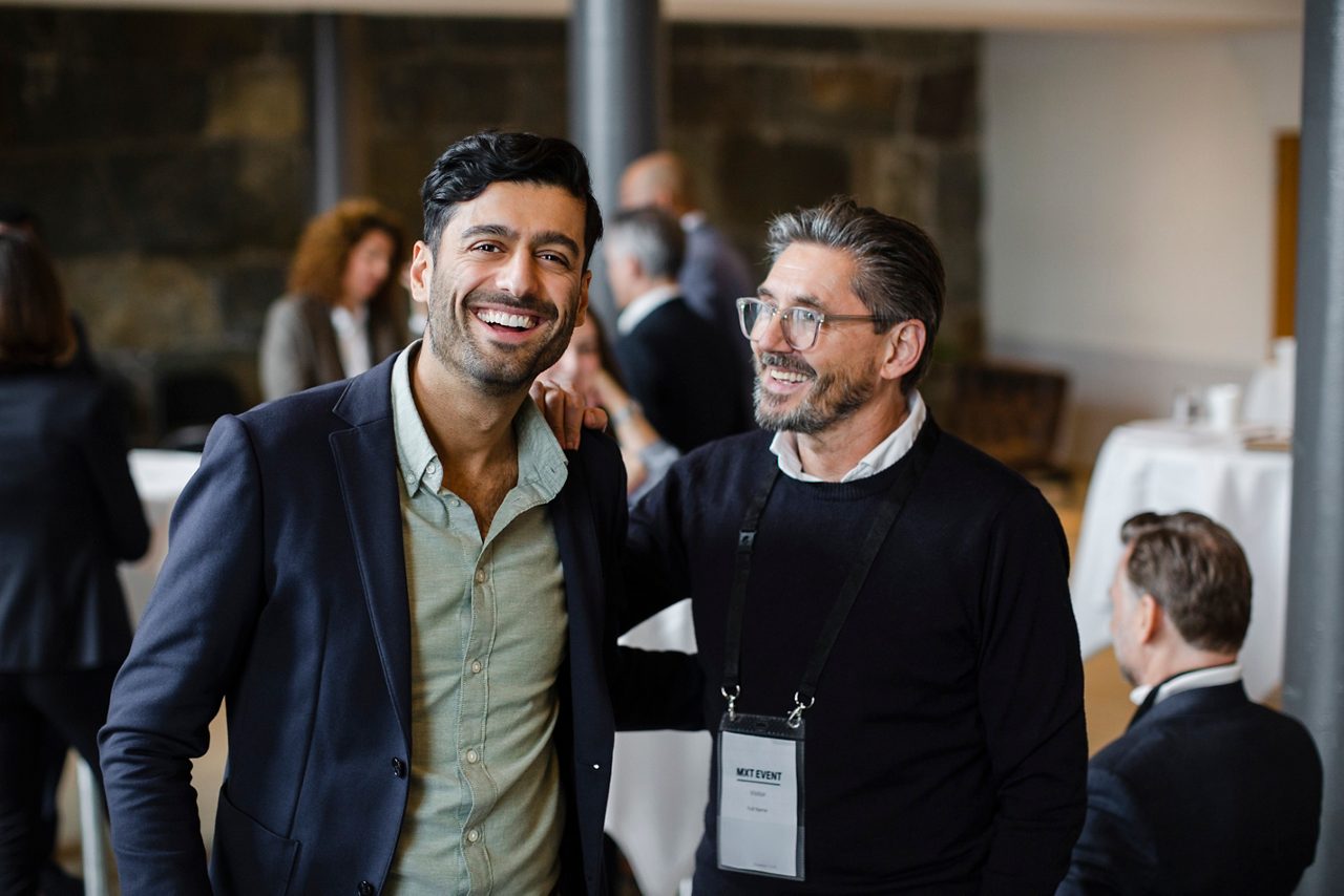 Two men at a business conference, smiling and hugging each other