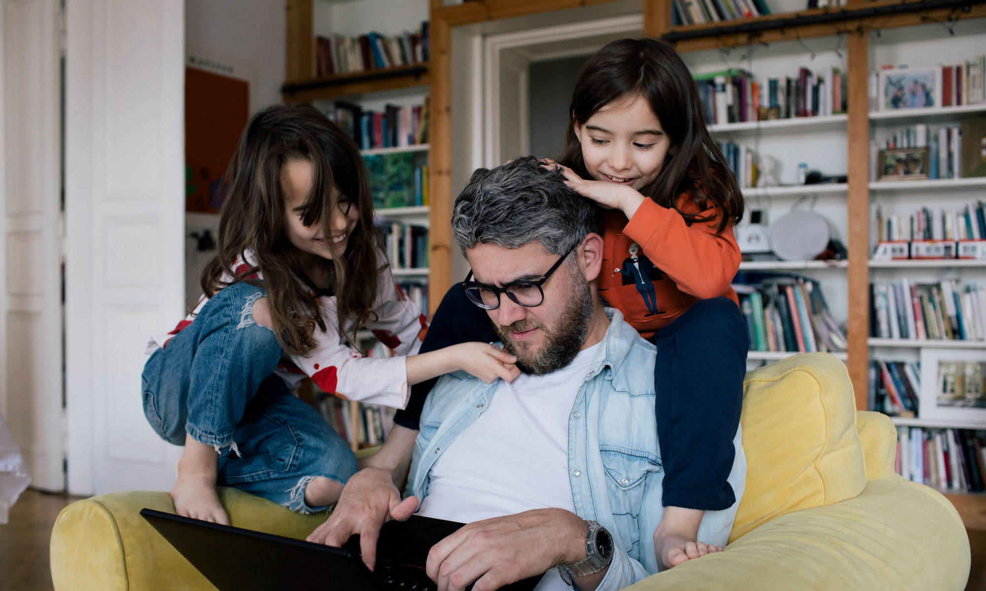 En man tittar på en bärbar dator tillsammans med två barn