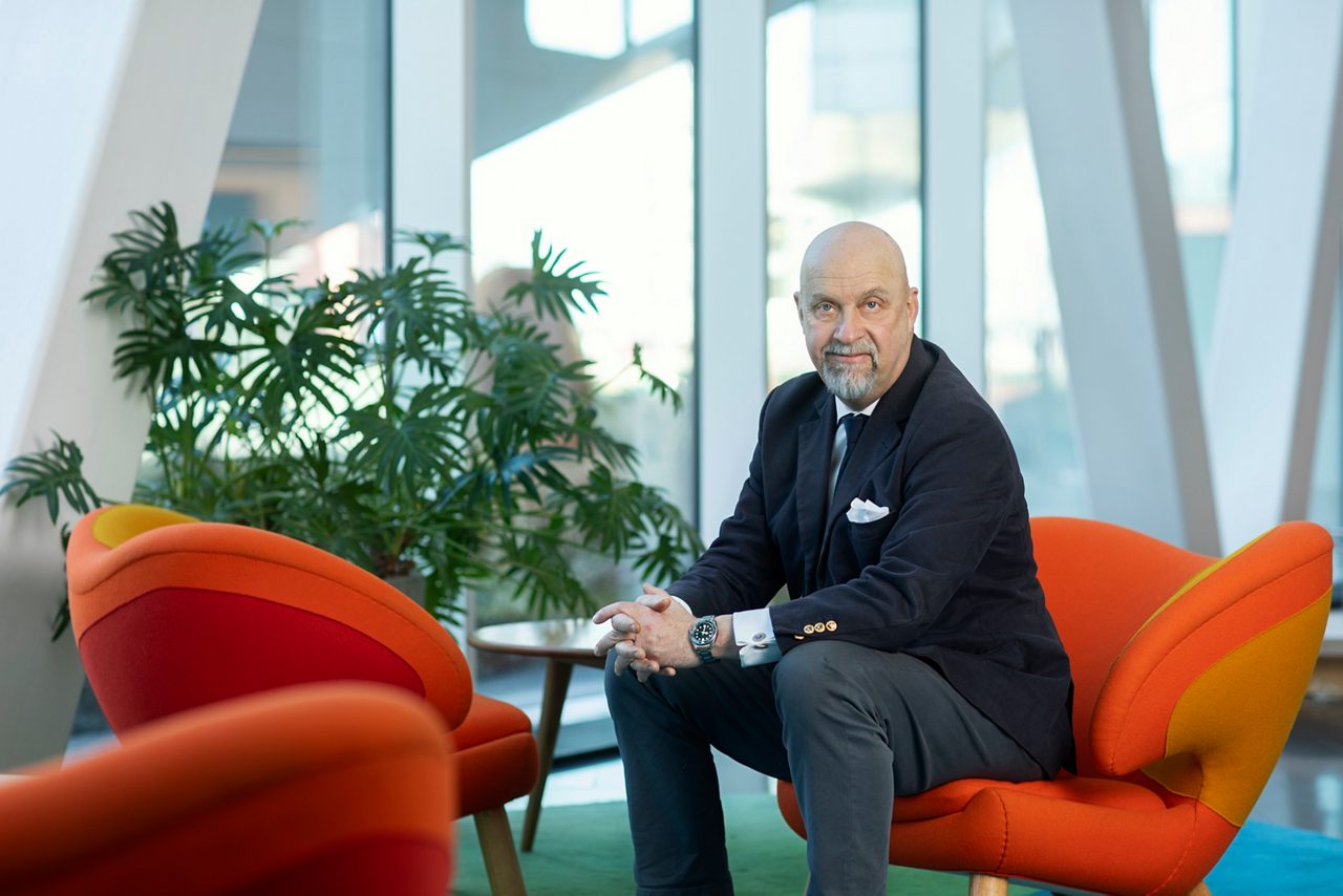 Olof Manner sitter i en orange fåtölj och tittar in mot kameran