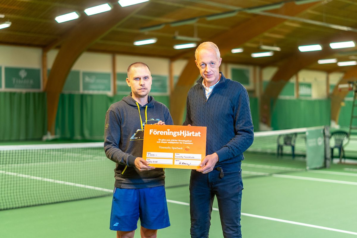 Per överlämnar en check till reprensentant i Tennisklubben. På Tennisbanan.