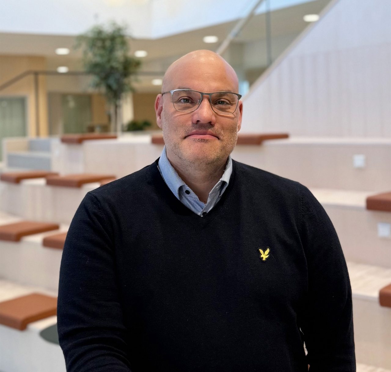 Man står och lutar sig mot ett ståbord, tittar in i kameran och ler