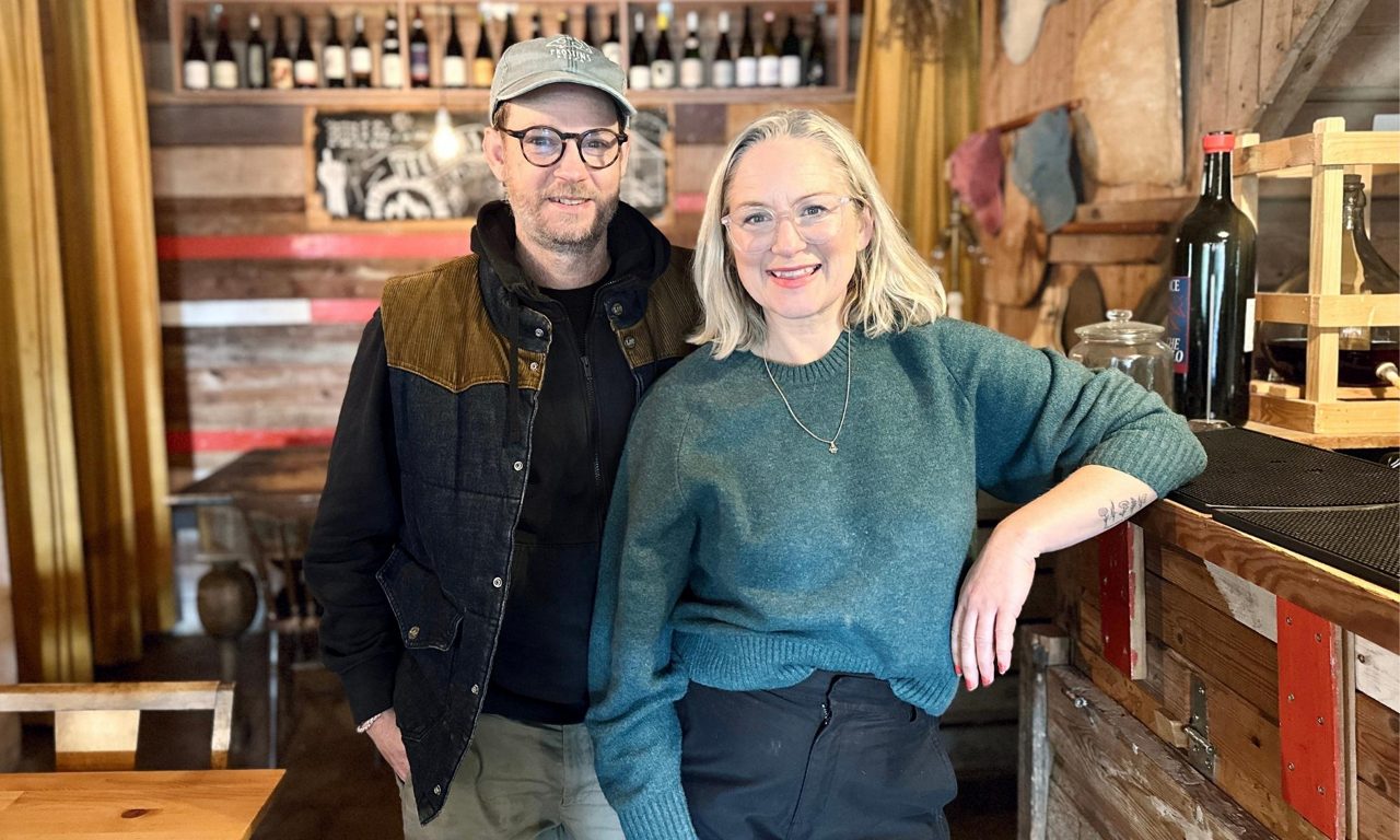En man och en kvinna står leende bredvid varandra, bakom disken inne på en  restaurang