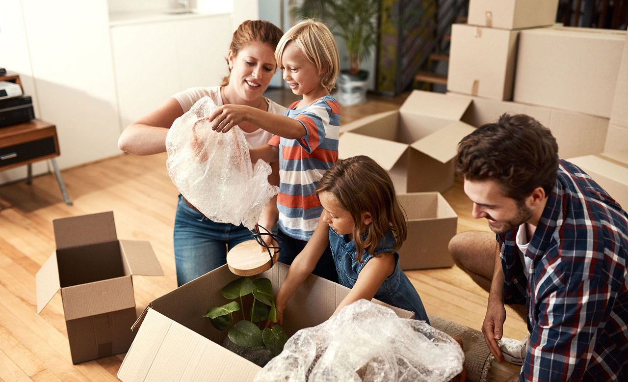 Family unpacking moving boxes in their apartment