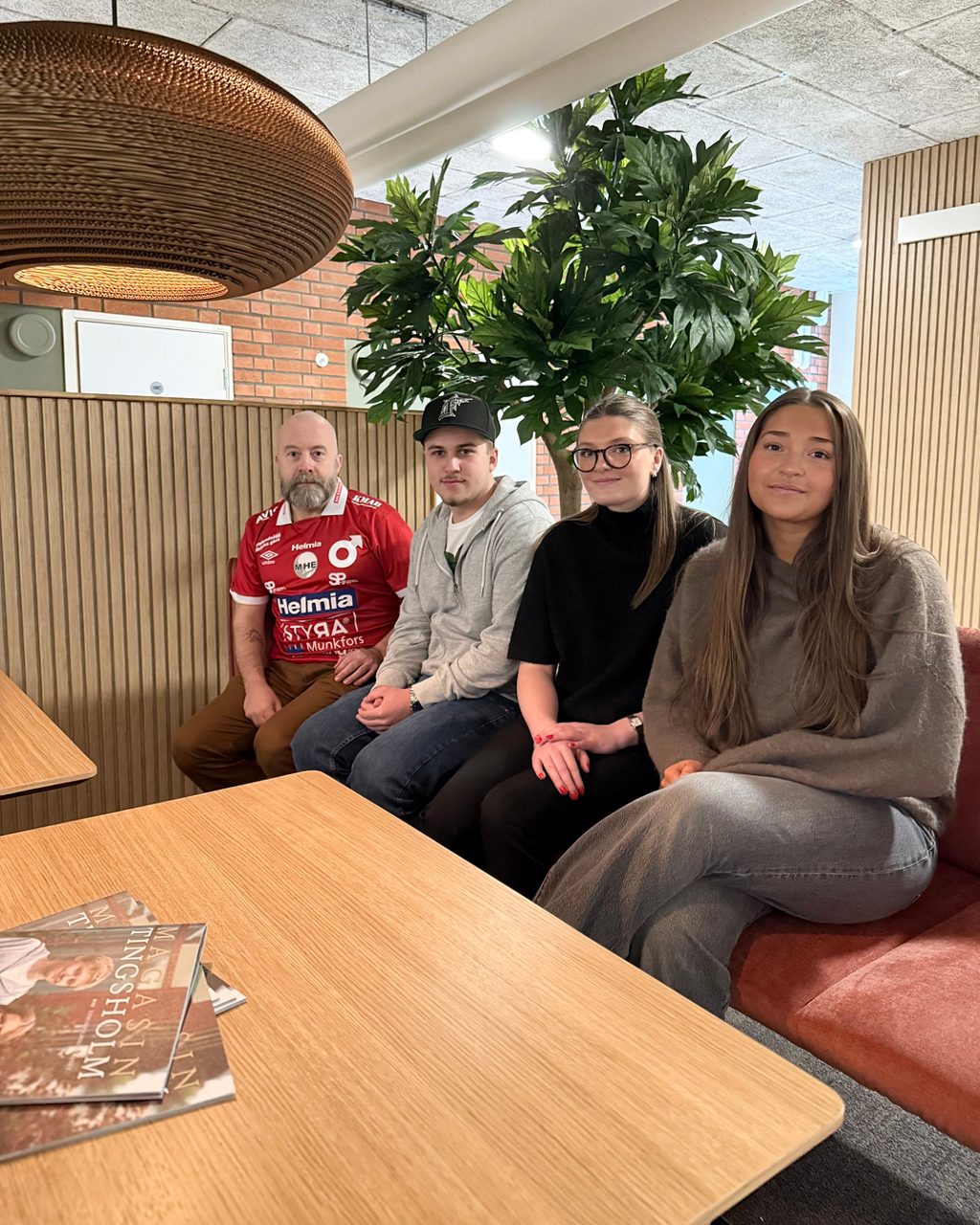 Fyra personer sitter en soffa, en man och tre elver