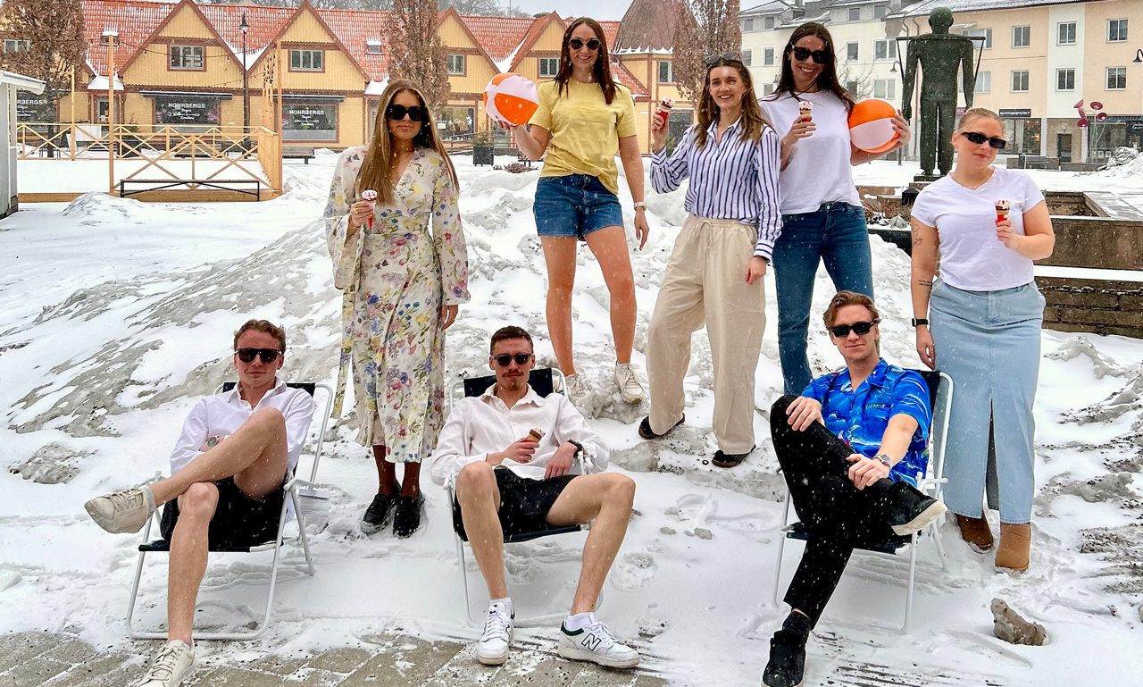 Personer står klädda i sommarkläder i en snödriva.