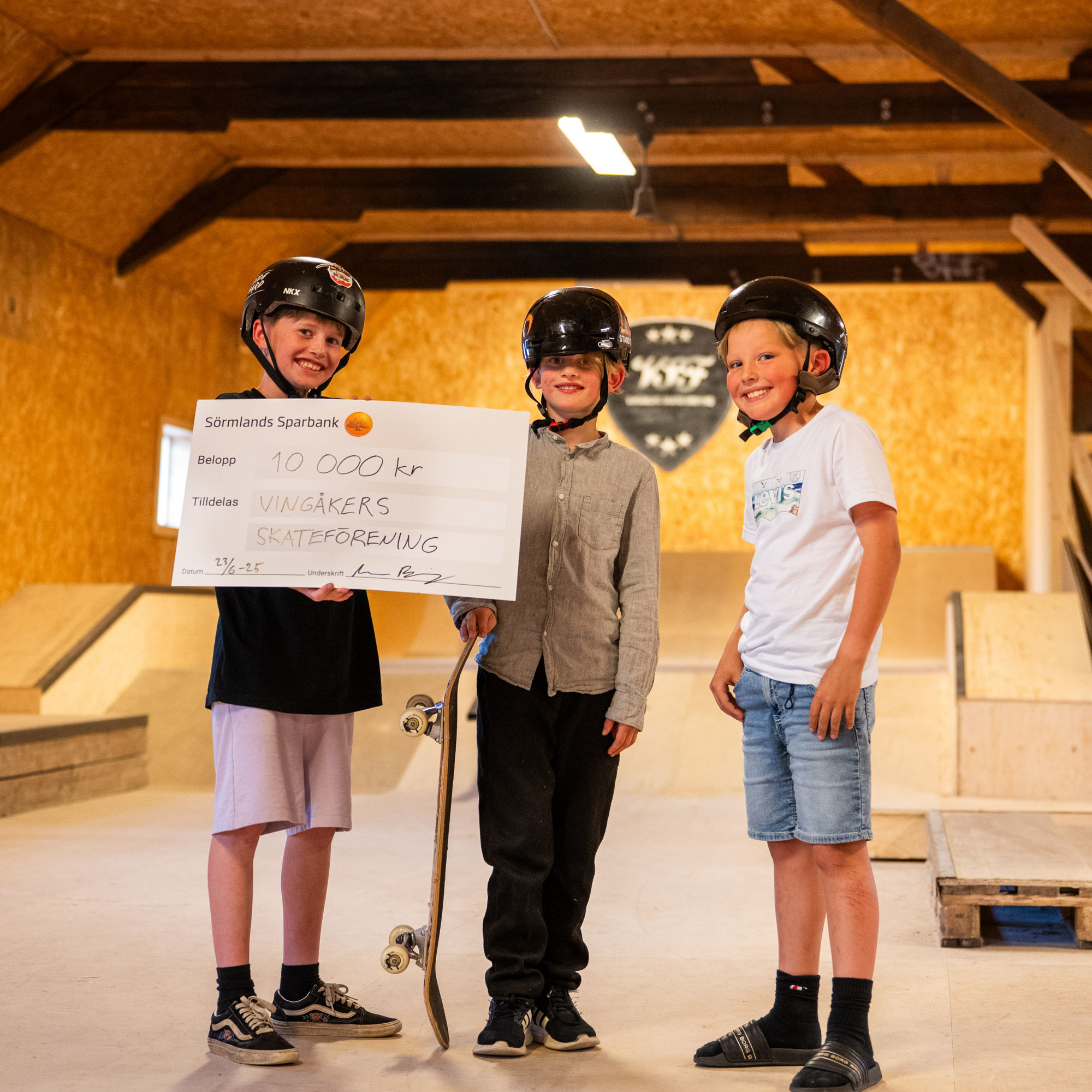 Tre barn håller i en check