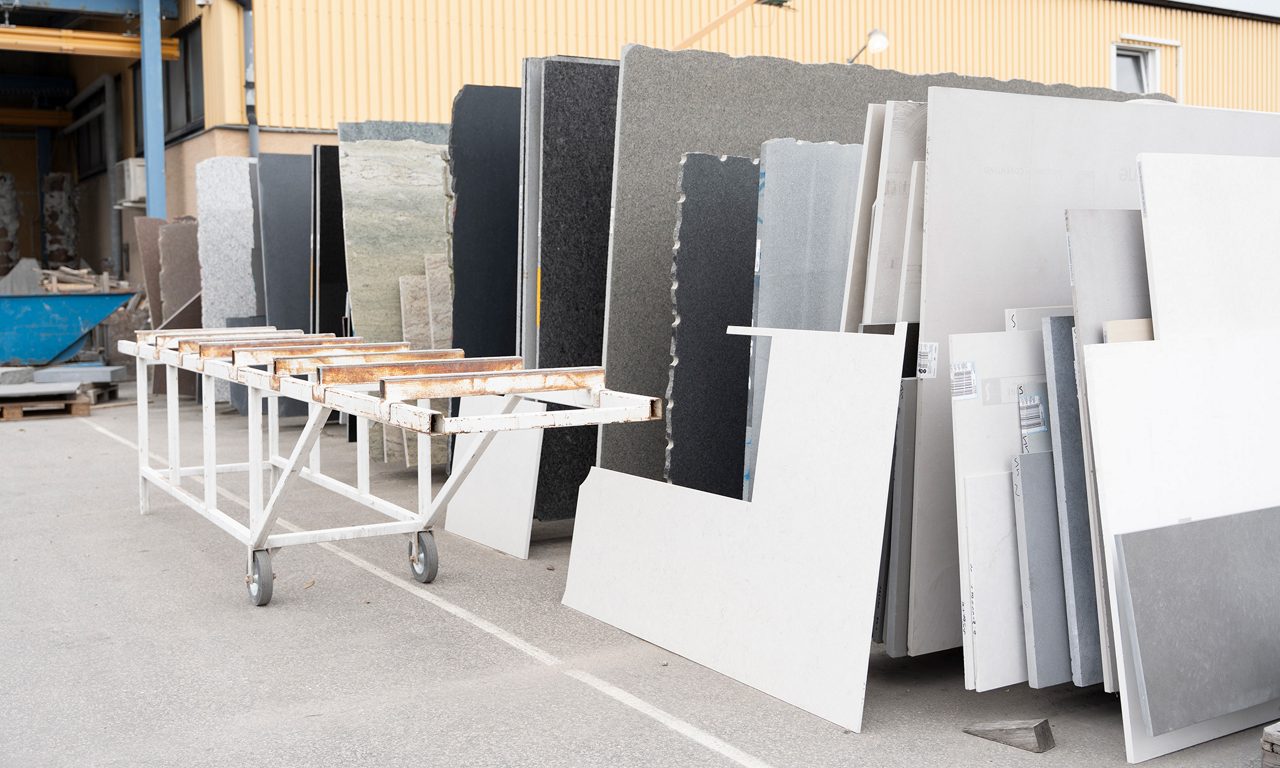 Stora stenskivor i olika material står uppställda på stenhuggeriets gård