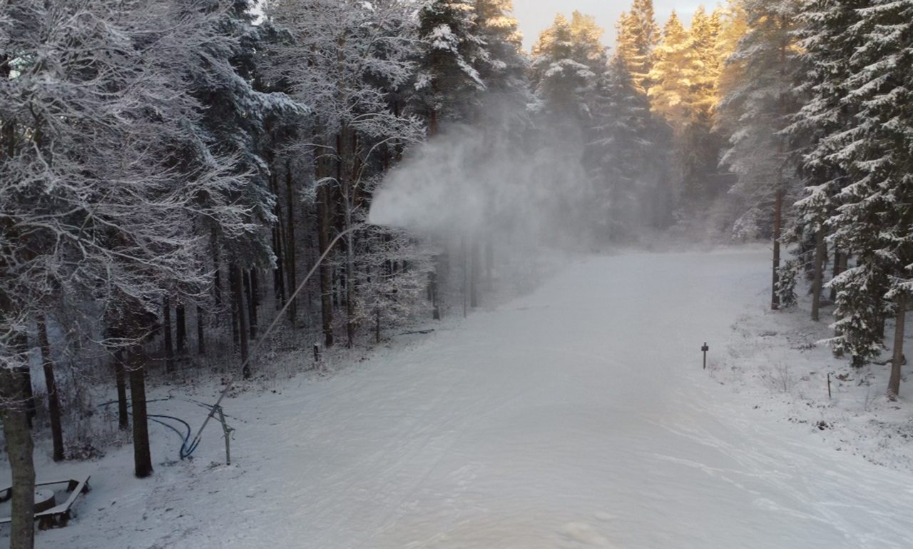 Snökanon förbereder ett skidspår i en snötäckt skog.