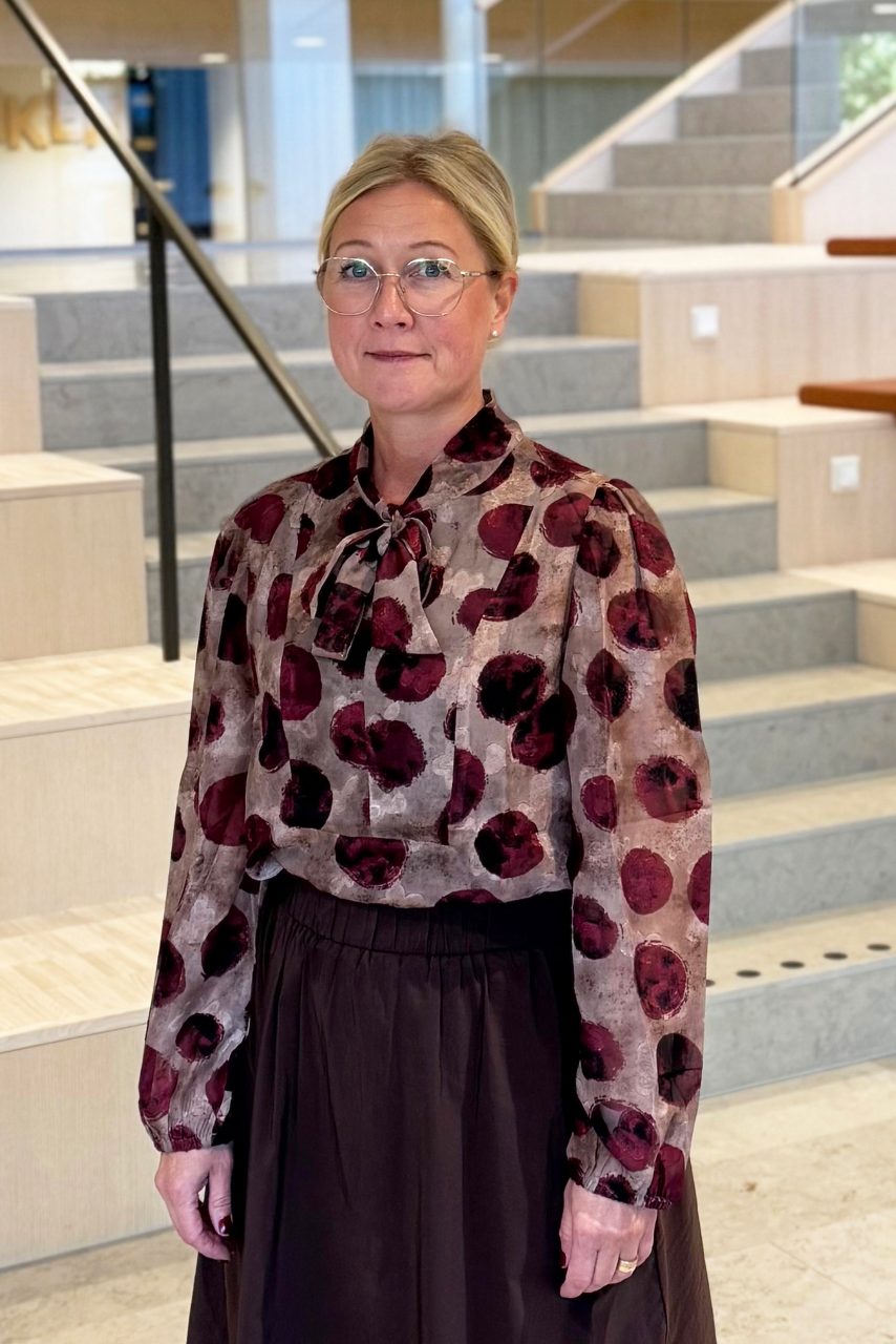 Kvinna tittar in i kameran och ler