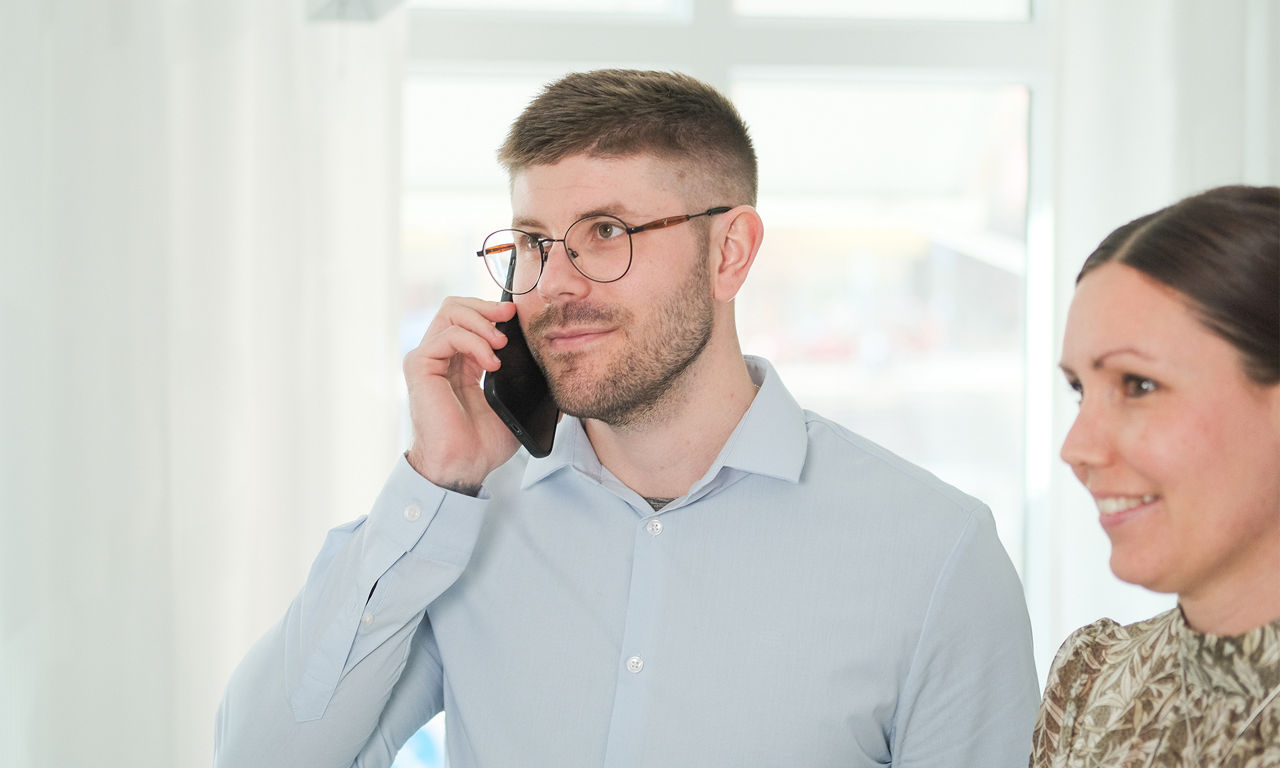 En ung man står och talar i mobiltelefon.