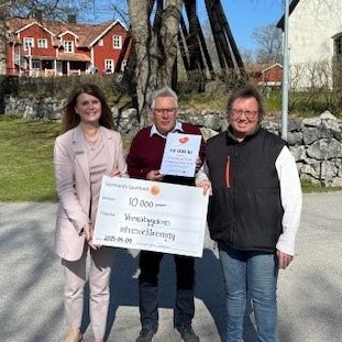 Tre personer som står utanför och håller i ett diplom