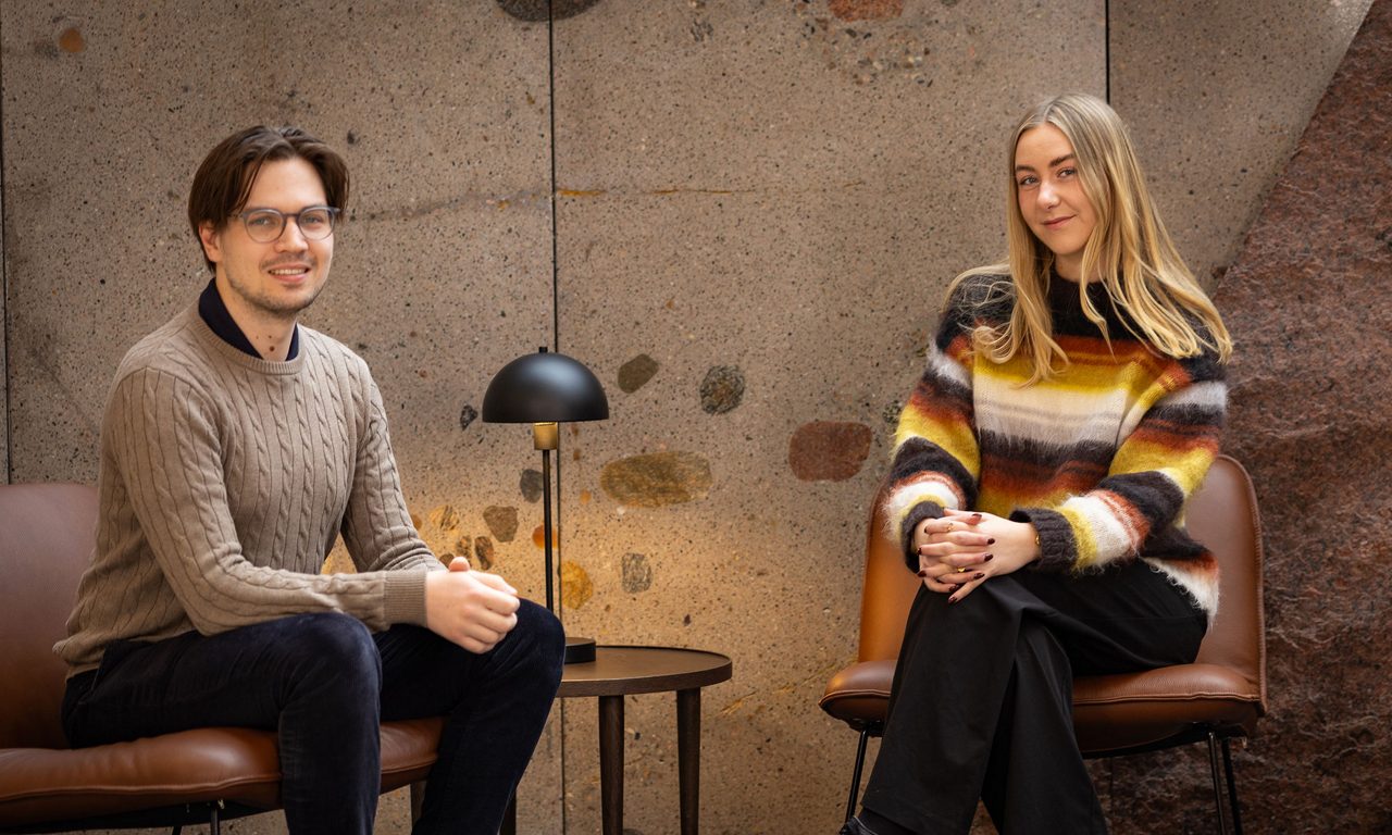 kvinna och man sittande i fotöljer ser ler mot kameran