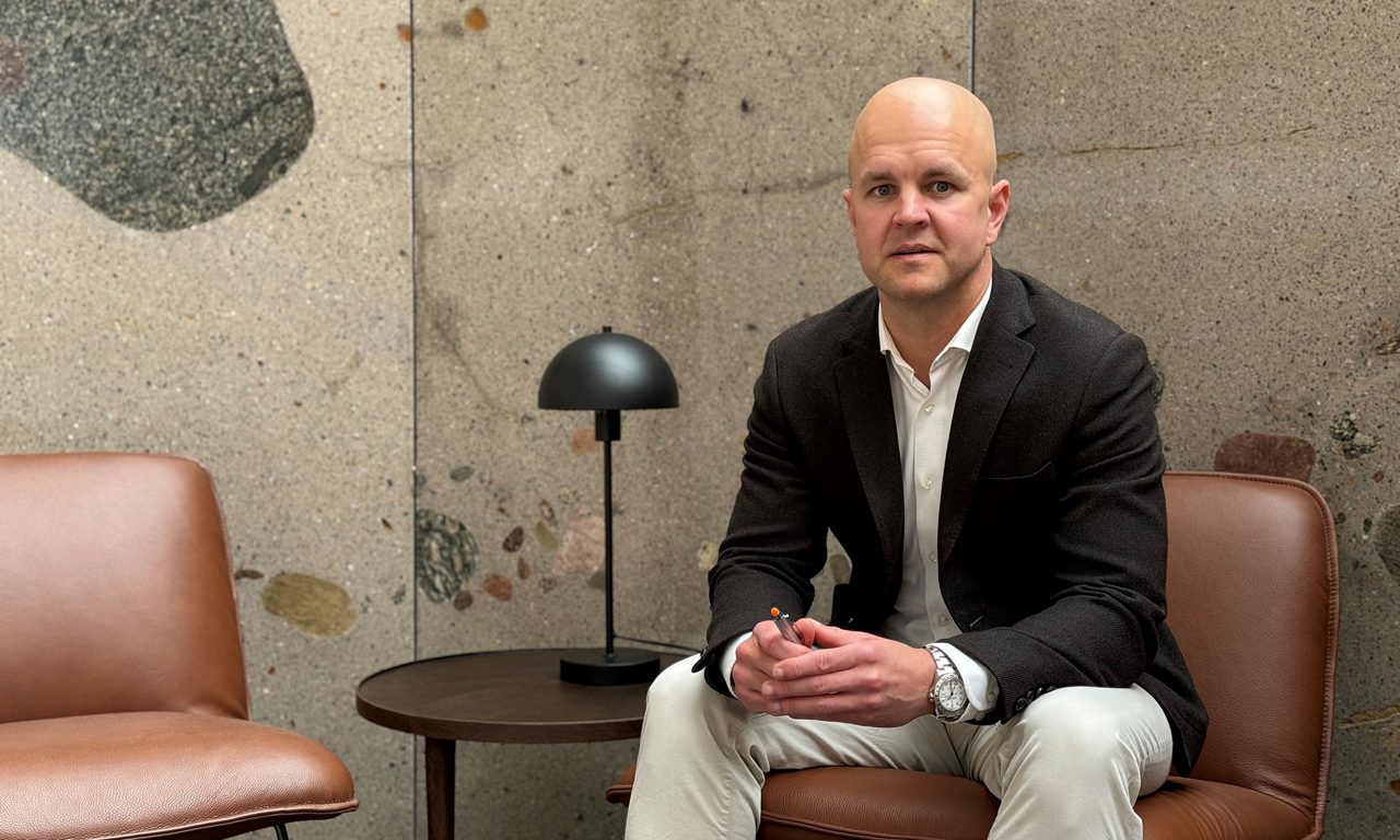 man i vit skjorta och svart kavaj sittandes på en skinnstol