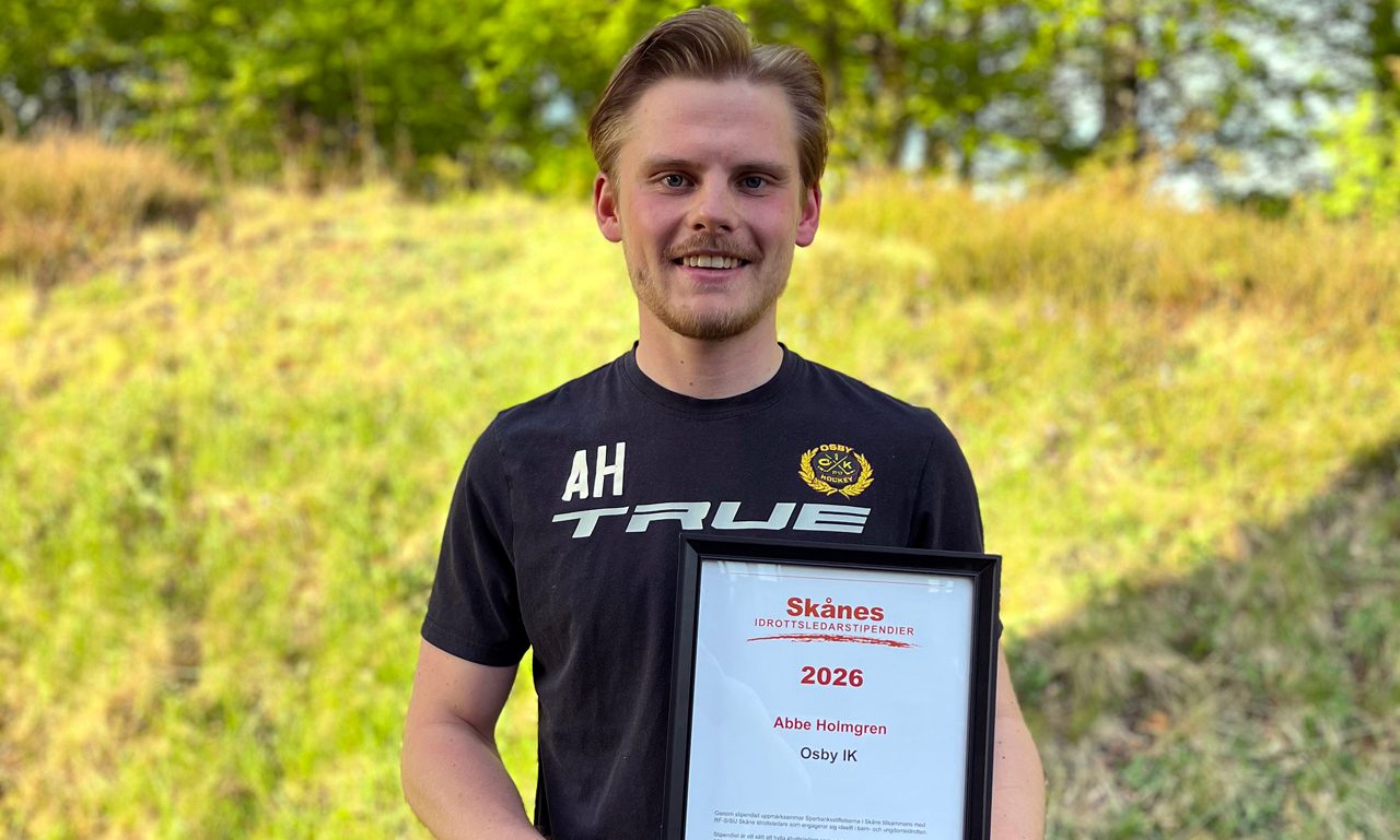 Ung man håller upp ett diplom.