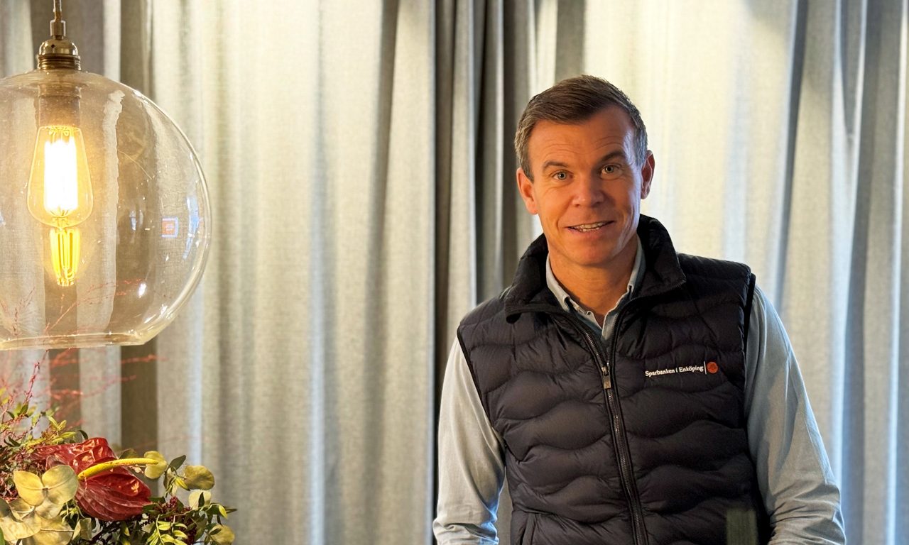 man i blå skjorta och svart Sparbanksväst ser in i kameran