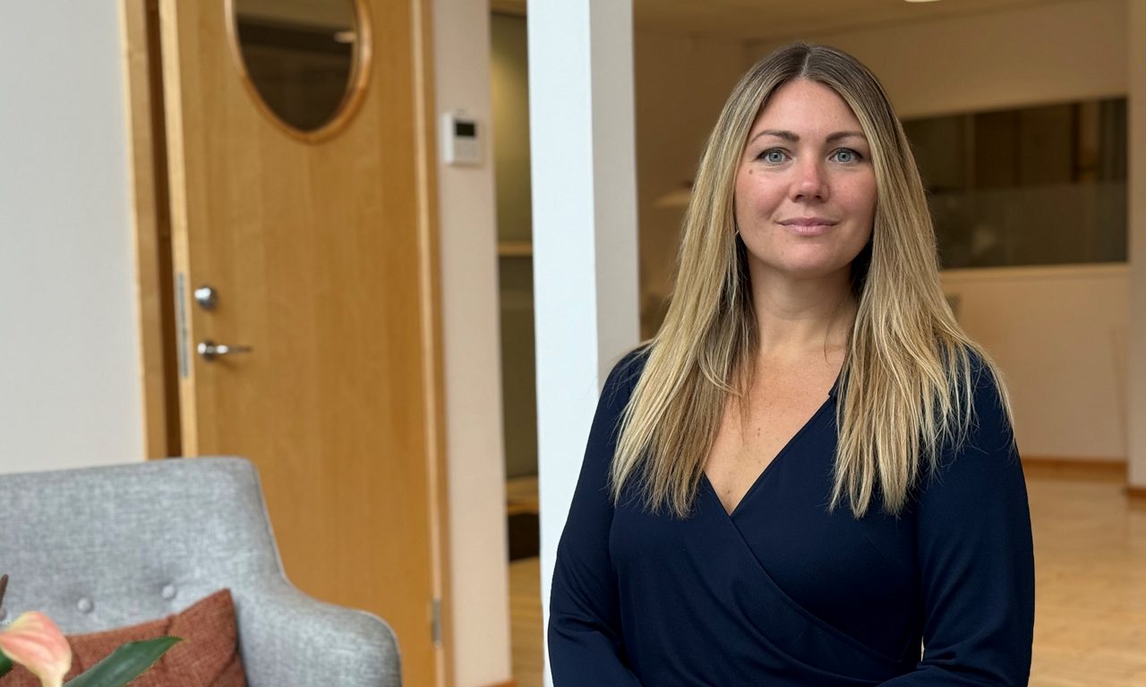 kvinna i kontorsmiljö ler mot kameran