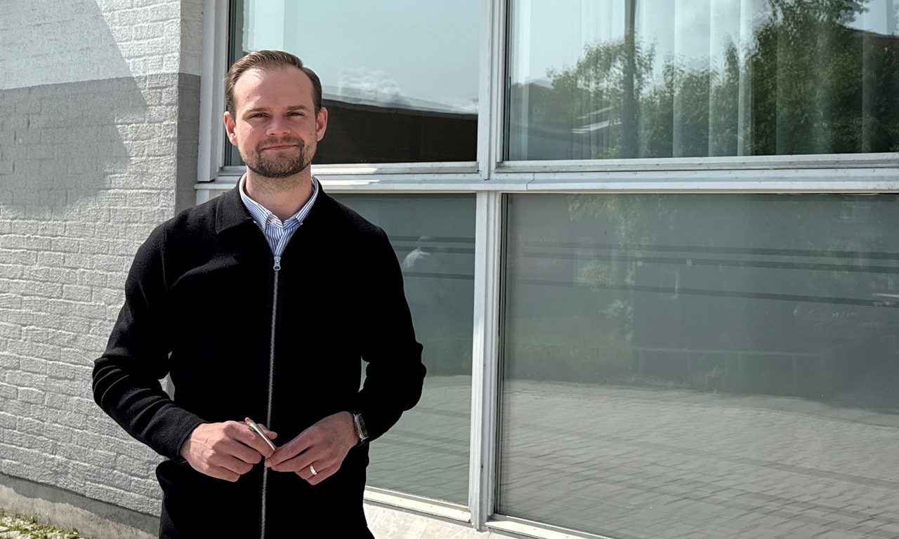 man  ler mot kameran utanför bankens lokaler i Kungsängeni bankmiljö