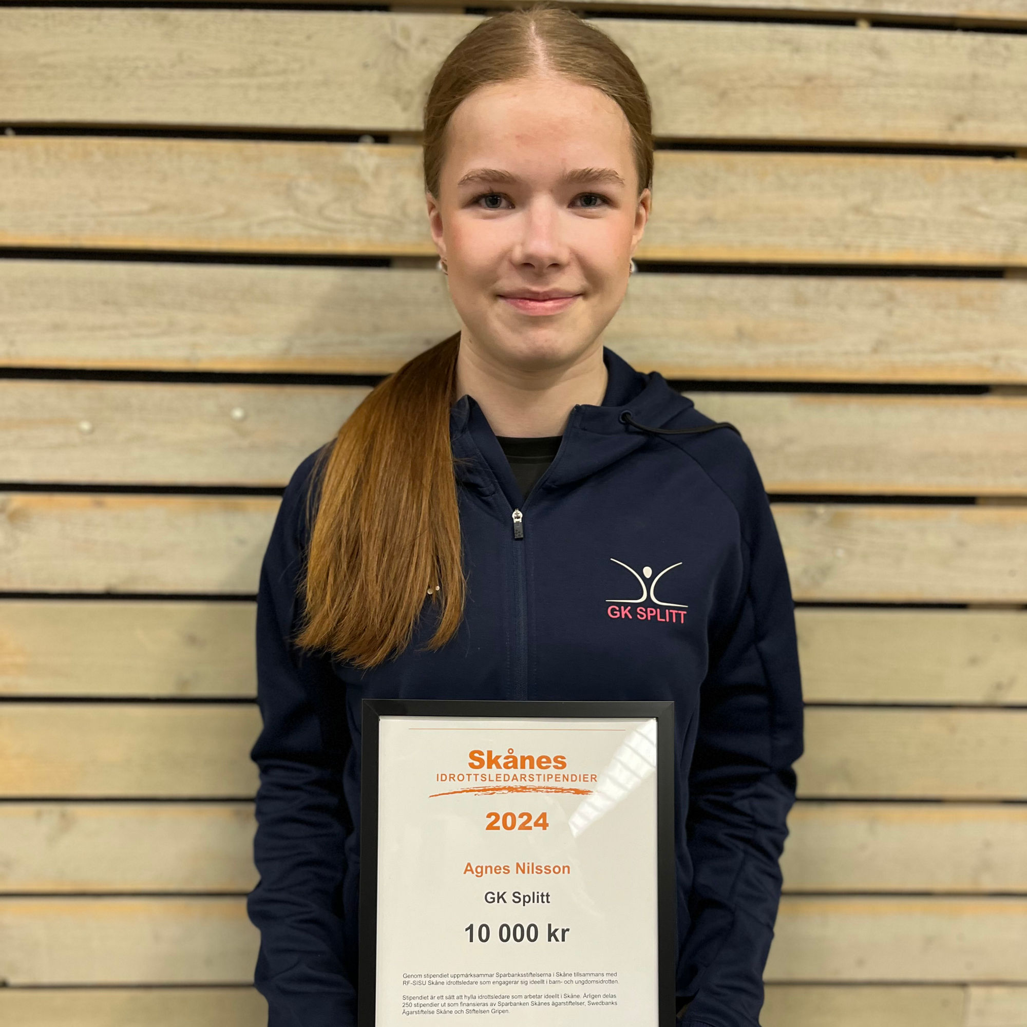 Agnes NIlsson står med sitt stipendie Skånes idrottsledarstipendie i händerna.