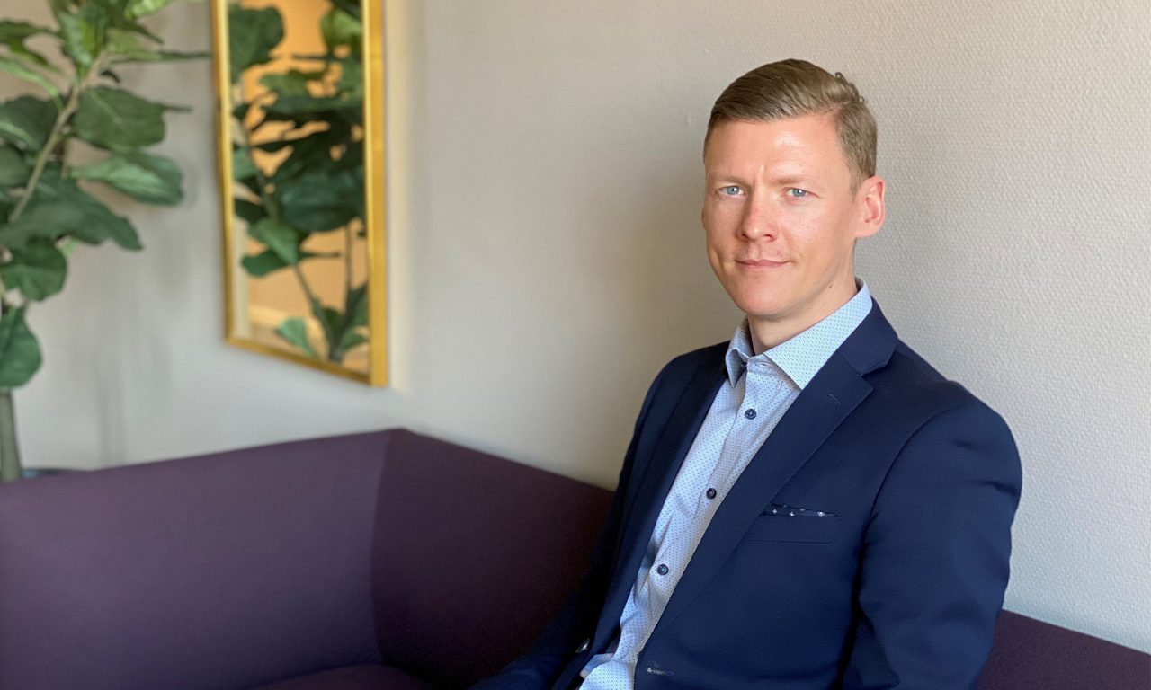 man i blå kavaj och skjorta ler mot kameran i bankmiljö