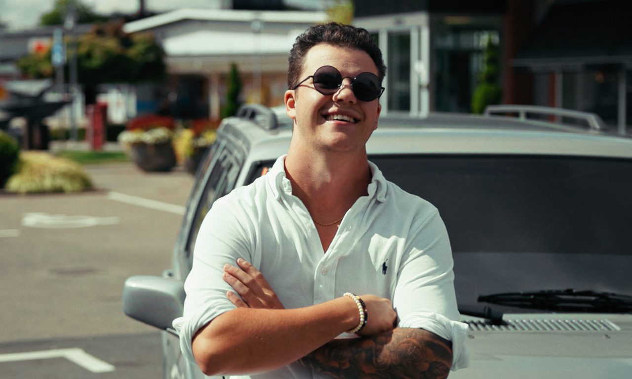 bild på en kille som står lutad mot en bil