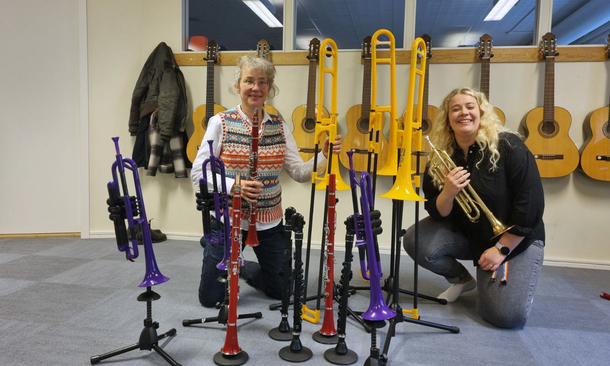 Två pedagoger på Kulturskolan i Tomelilla sitter bland instrument och håller trumpet och klarinett i handen.